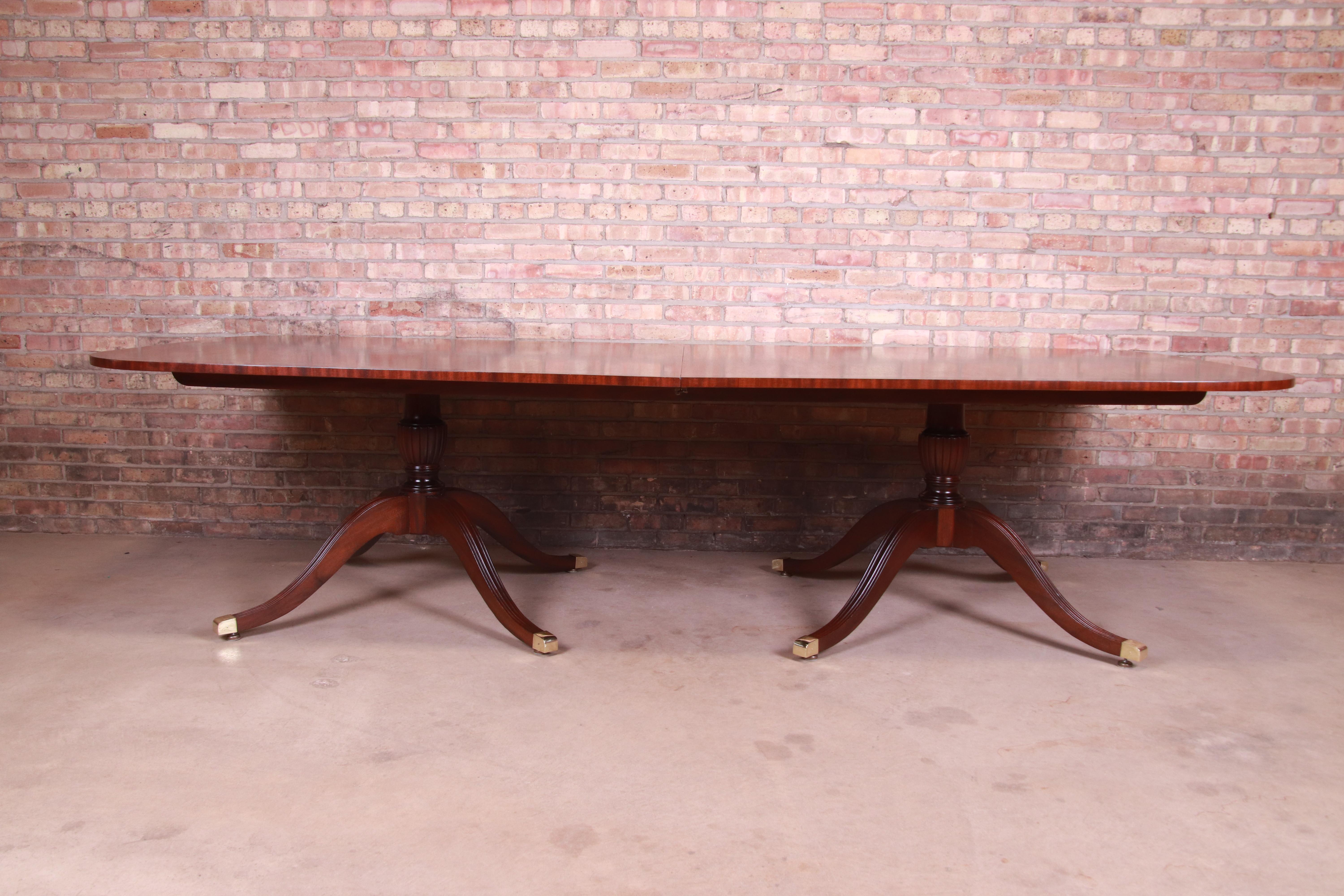 An exceptional Georgian style double pedestal banquet dining table

By Councill Furniture,

USA, circa 1980s

Book-matched banded mahogany with satinwood inlay, carved solid mahogany pedestals, and brass-capped feet.

Measures: 120