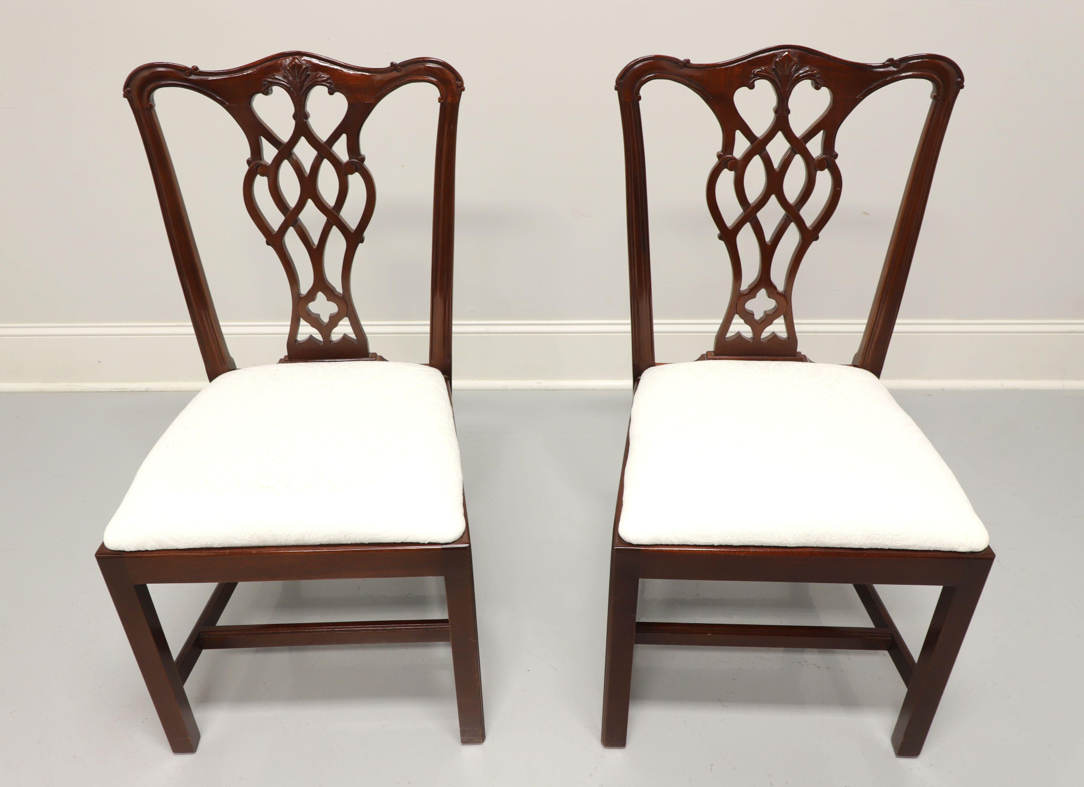 A pair of Chippendale style dining side chairs by Councill. Solid mahogany with carved crest rail, backsplat, straight legs and stretchers. Seats upholstered in a neutral cream colored brocade fabric. Made in the USA, in the late 20th