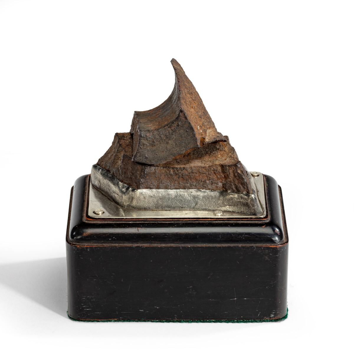 Count Gleichen’s Russian shell paperweight,  the tooth shaped fragment of a Russian armament shell set above another of rectangular form both raised on a silver mount on an ebonized rectangular plinth, applied with a plaque reading ‘Two fragments of