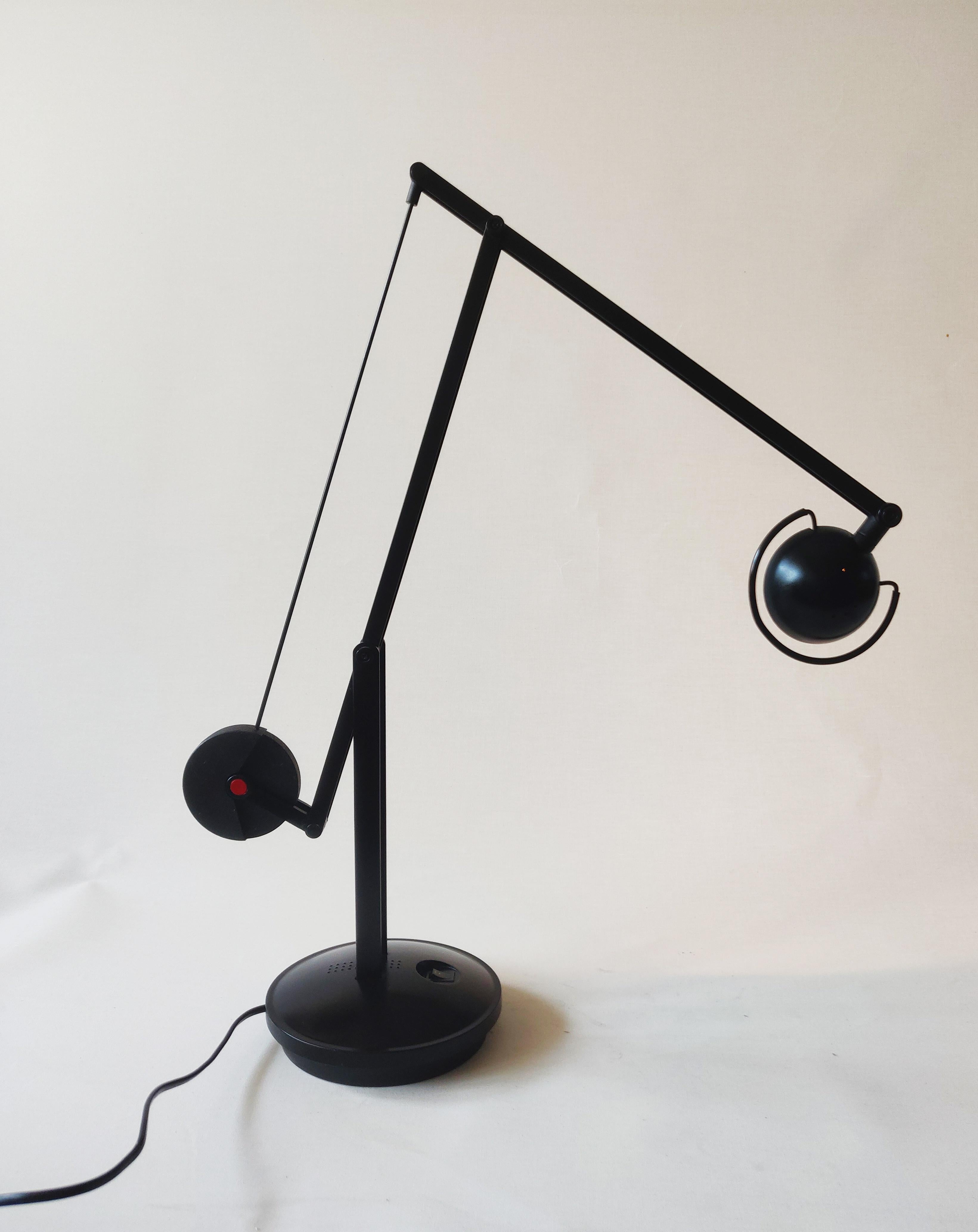 Black metal Architect desk lamp with counterweight and red details, reminiscent of the Memphis Group style.
The desk lamp can be placed in countless different positions. The heavy base has a diameter of 18 centimeter, the first arm(mounted on the
