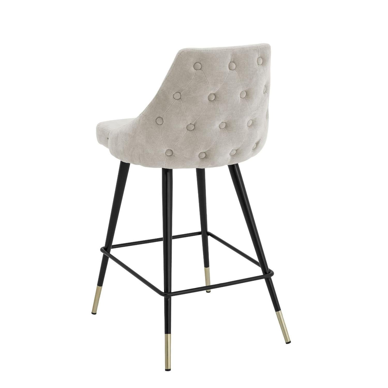 Counter stool in light grey fabric black metal feet and brass finishes.