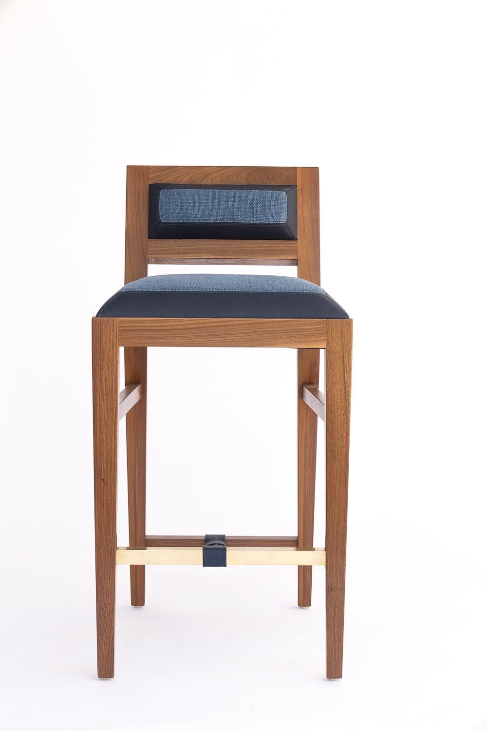 The solid walnut counter stool is handcrafted with traditional joinery. Shown in a combination of leather and fabric upholstery. This is a homage to 1940s French designer Jacques Adnet. Custom sizes and finishes available.