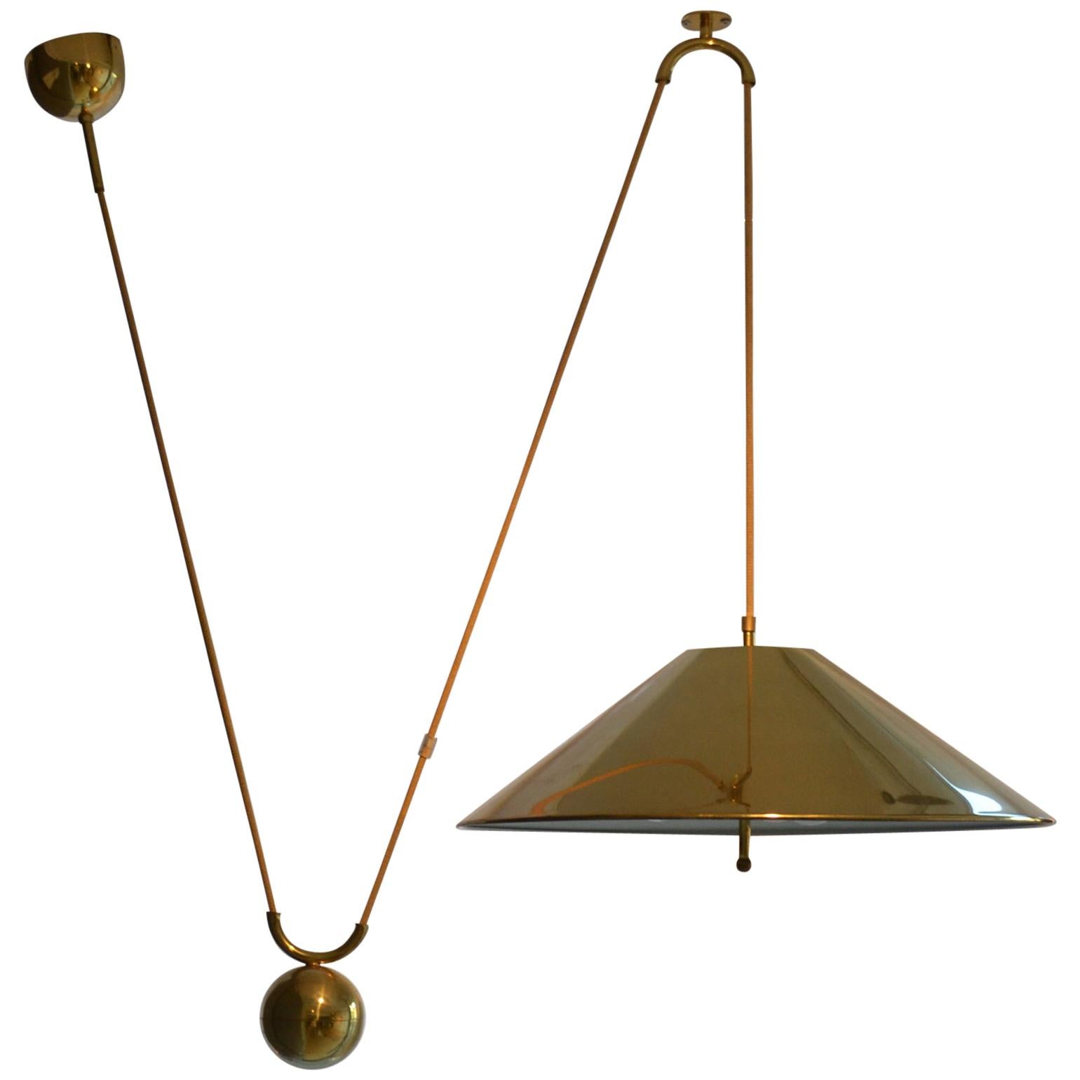 Counterbalance pendant 'Keos' by Florian Schulz with side weight. Strong and minimal pendant in a high quality brass moves smoothly up and down due to the solid brass counterweight. The shiny brass polished brass is coated. The shade holds three