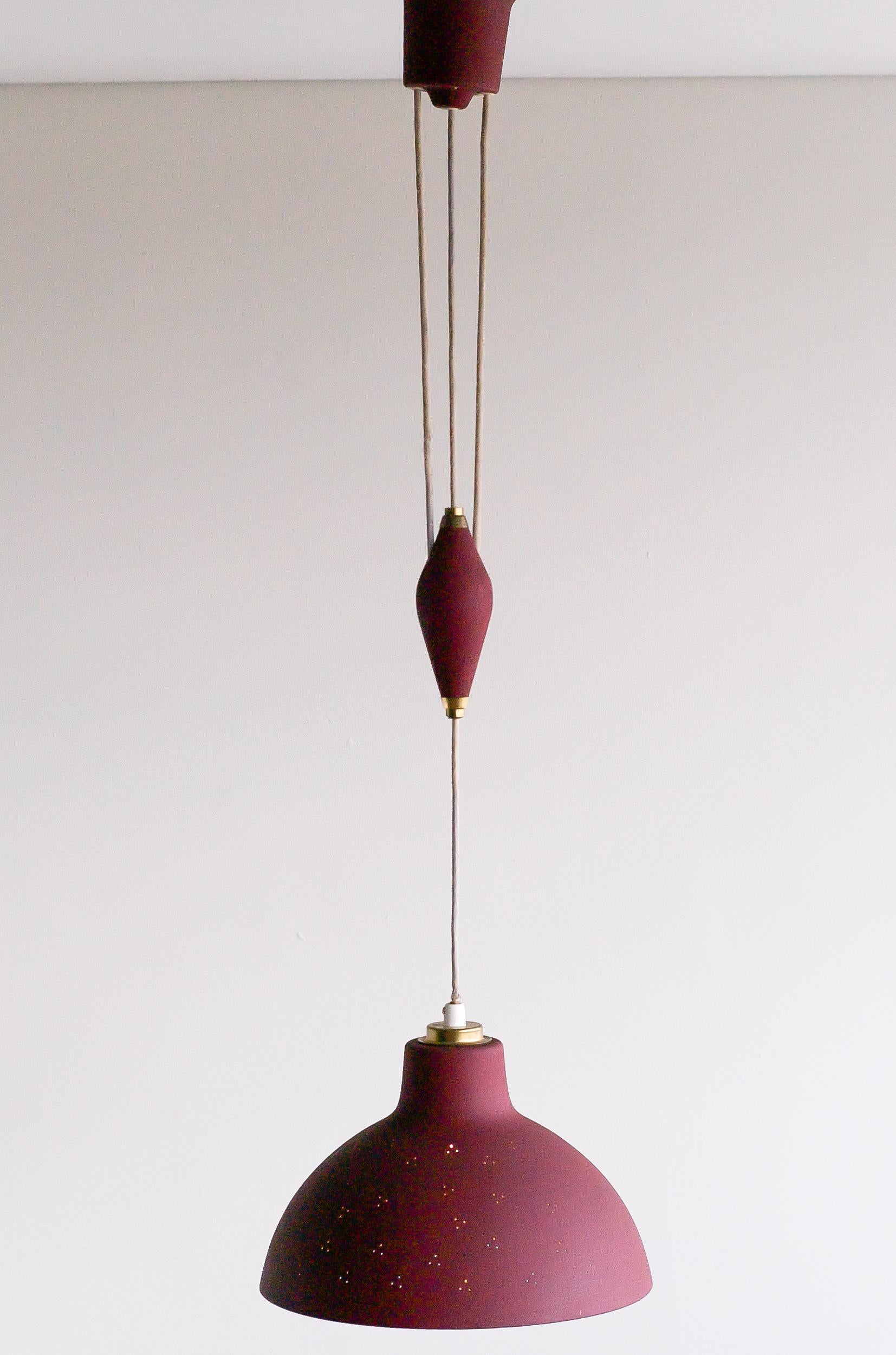 Counterbalance pendant lamp made by Nordiska Kompaniet, NK, Sweden.
The shade, counterweight and ceiling cap are covered with beautiful oxblood red wrinkle paint.
The shade has a perforation pattern identical to Paavo Tynell designed