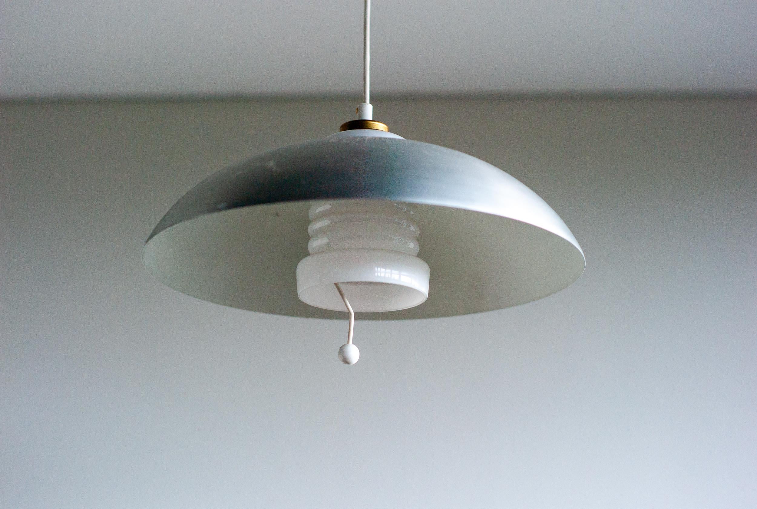 Beautiful adjustable Nordiska Kompaniet pendant made in 1950.
The shade and ceiling cap are made in polished aluminum. 
The counterweight is made of green porcelain.
The inside shade is made of white glass. Height is variable. 
Marked NK