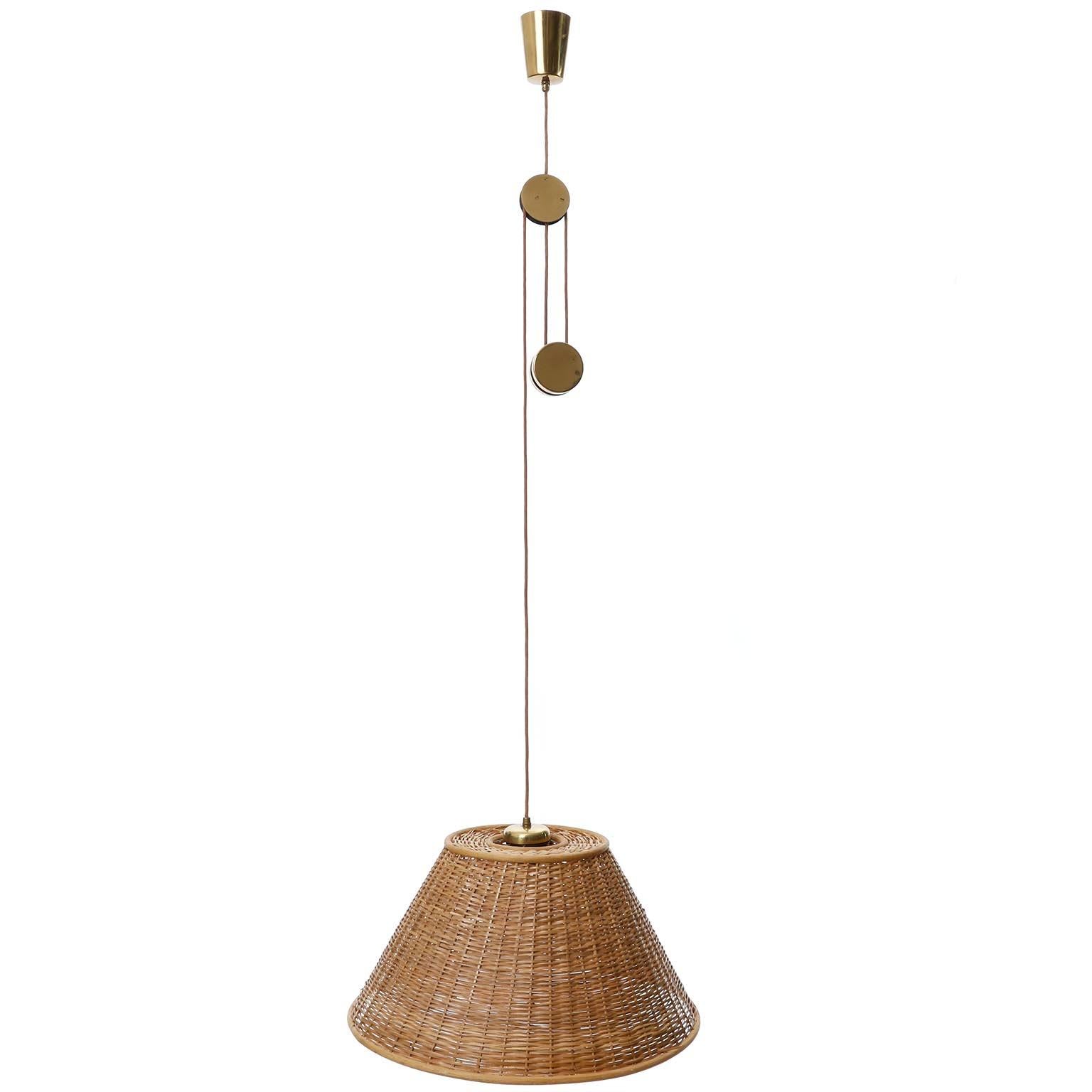 Rare et fantastique lampe suspendue en laiton à hauteur réglable avec abat-jour en osier modèle 'Jo-Jo Zug' no. 2505 par J.AT&T. Kalmar a été fabriqué au milieu du siècle dans les années 1950.
Le luminaire s'inspire d'un design de Josef Frank datant