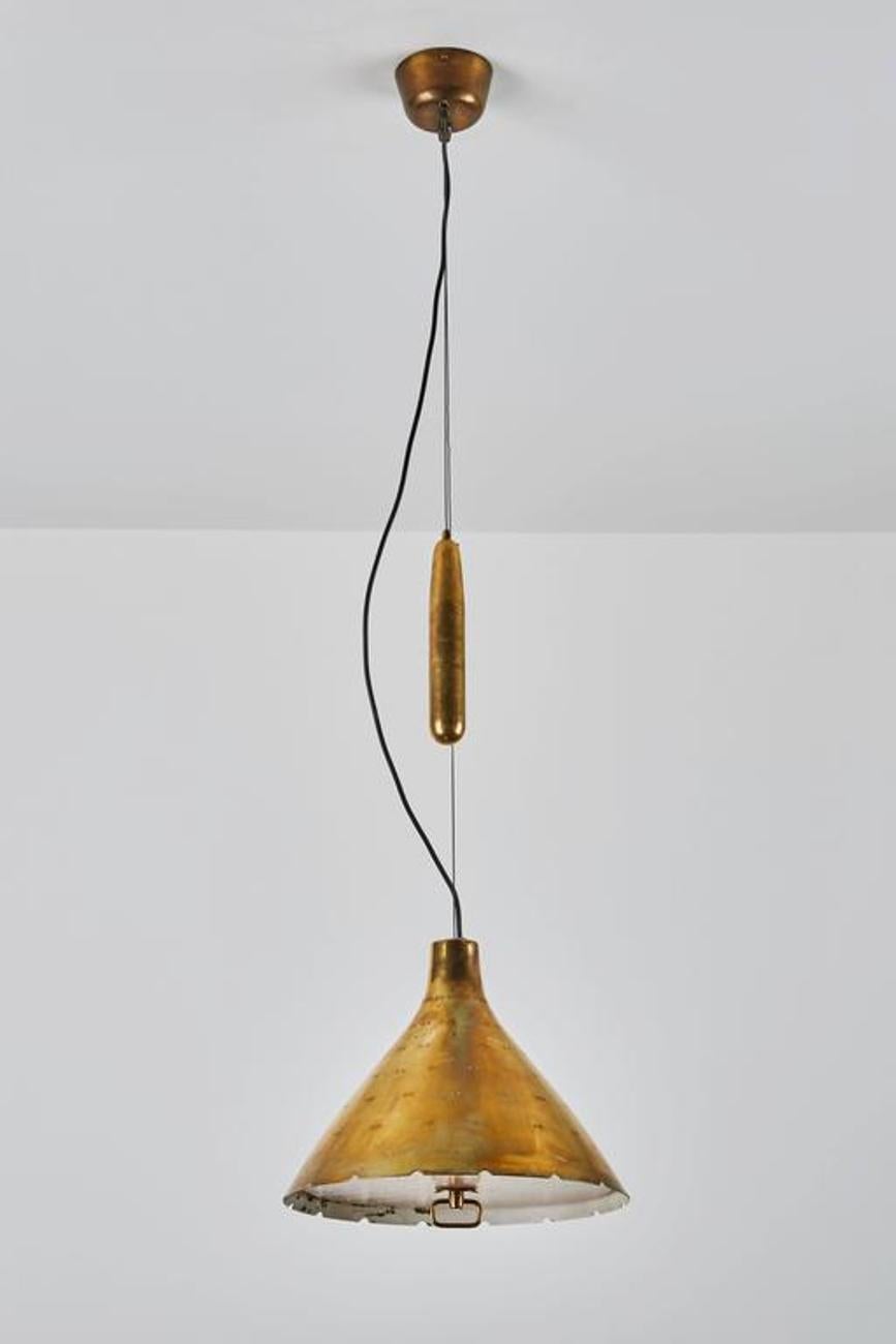 Counterweight pulley pendant with perforated shade and glass diffuser. Designed by Paavo Tynell in Finland, circa 1950s. Pulley is solid brass. Wired for US junction boxes. Takes one E27 100w maximum bulb.
