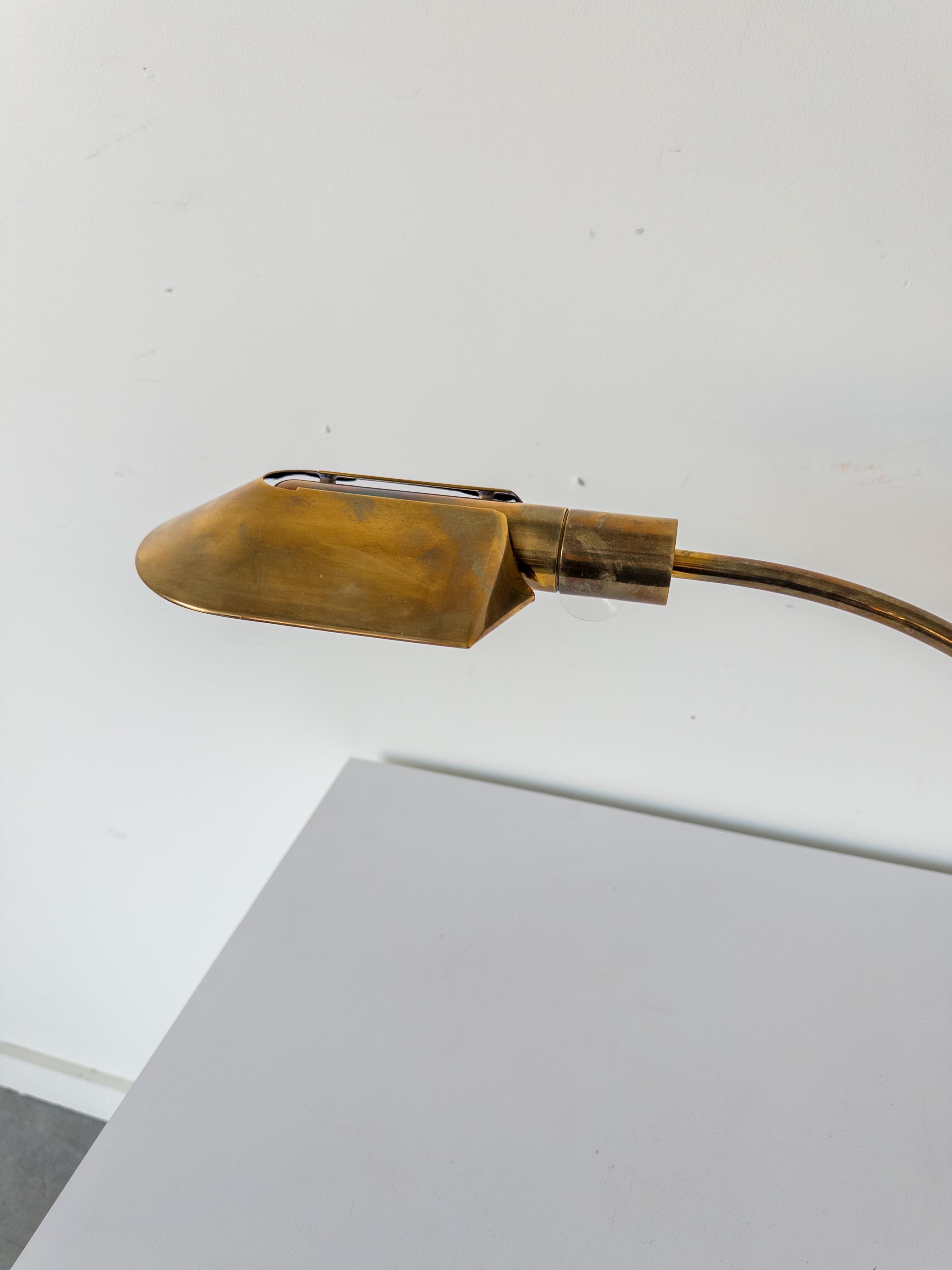 A counterweighted brass desk lamp having a rounded shade and curved chromed arm. The lamp rotates on a round nylon base with a suspended counterweight supporting the shade.

