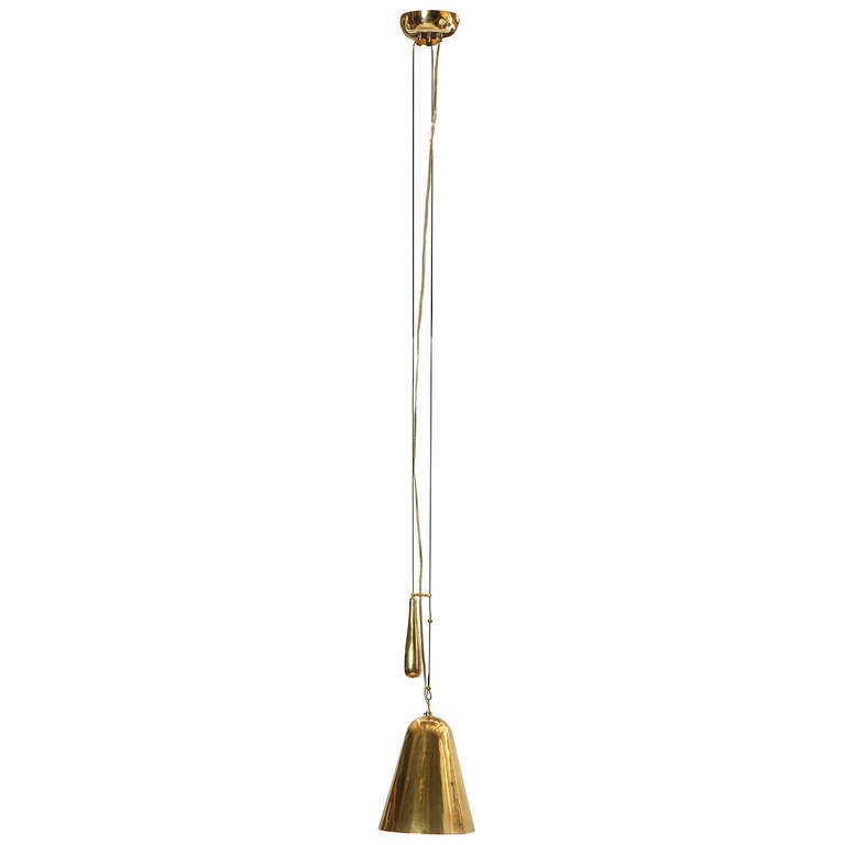 An uncommon and masterful Scandinavian Modern ceiling fixture designed by Paavo Tynell. This adjustable pendant lamp features a brass bell-shaped dome with a counter-weight and pin-hole perforations. Manufactured by Taito Oy in Finland, circa