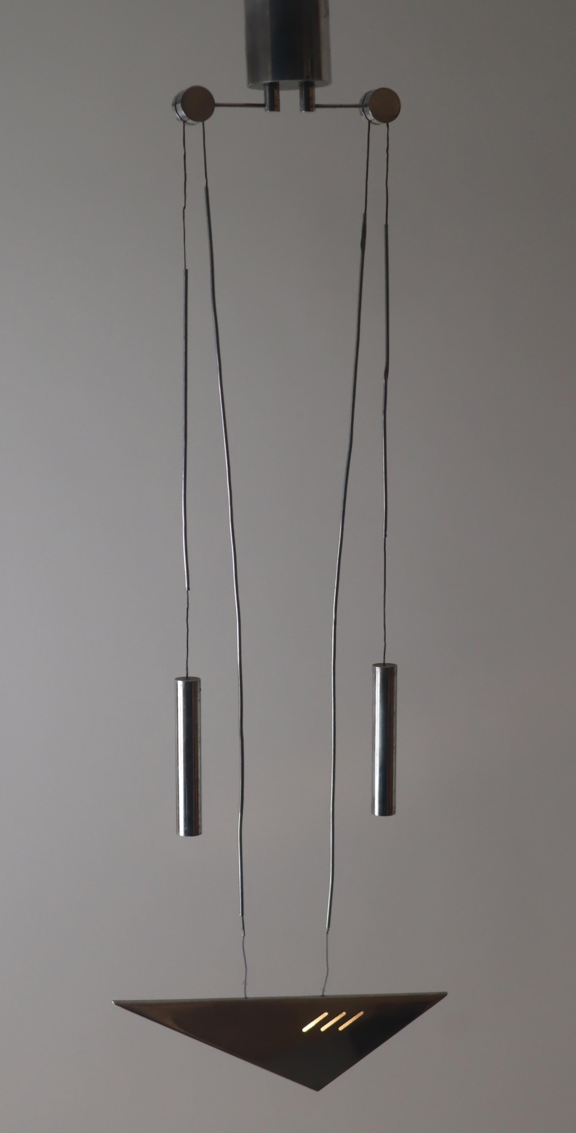  This very sleek handcrafted counterweight lamp is made of aluminum. It has a minimalist appearance and can be adjusted in height. This lamp is equipped with a 12 volt transformer that illuminates a halogen light bulb in the lampshade. In front of