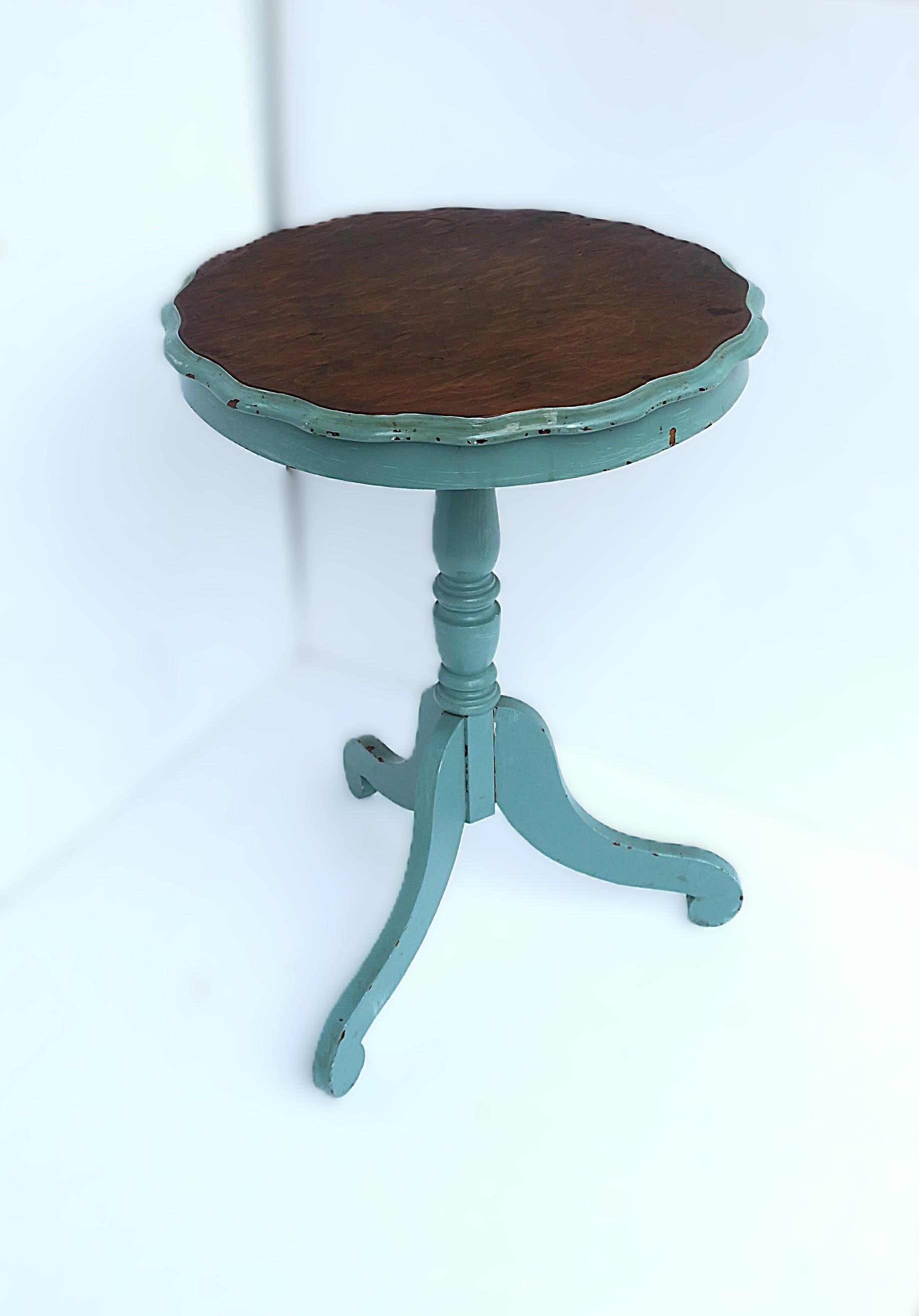 Table d'appoint ou d'appoint en bois, de style Country, vers la fin du 20e siècle. Cette table en bois est ronde, avec une teinte turquoise (peinture) et un brun riche (bois), un plateau et un bord festonnés, et une base à trois pieds. Une certaine