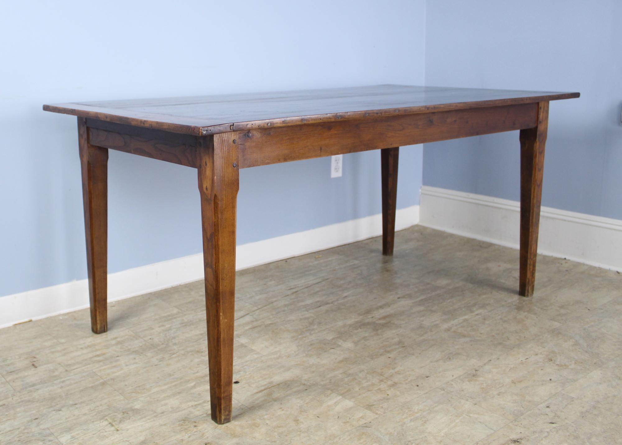 A smaller farm table in well grained elm with breadboard ends. The top is in very good condition with little distress. The legs are classically tapered and pegged at the apron in the traditional manner. The apron height of 24.75