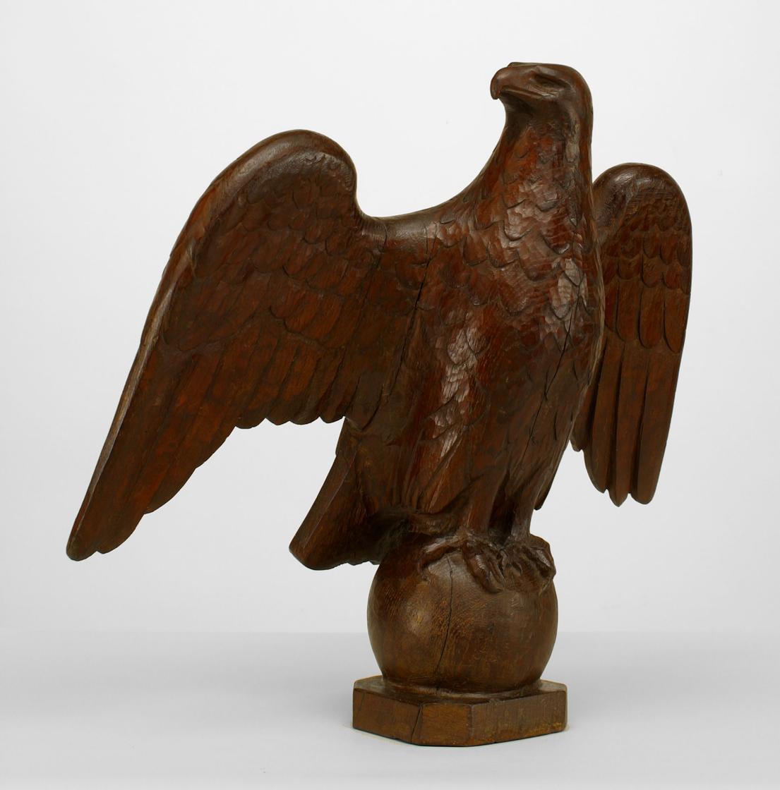 Figurine en chêne sculpté de style American Country (France 19e/20e siècle) représentant un aigle aux ailes déployées et perché sur une base en forme de globe (signée : M. Granolt) (NFS)