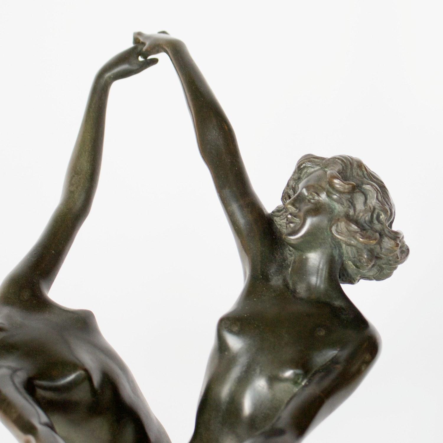 'Danse Pasterale' an Art Deco bronze sculpture by Claire Jeanne Roberte Colinet, depicting two intertwined dancing ladies. Original dark green bronze patination. Set over a variegated marble base with cast gilt bronze reliefs of 'Pan with Pipes' and
