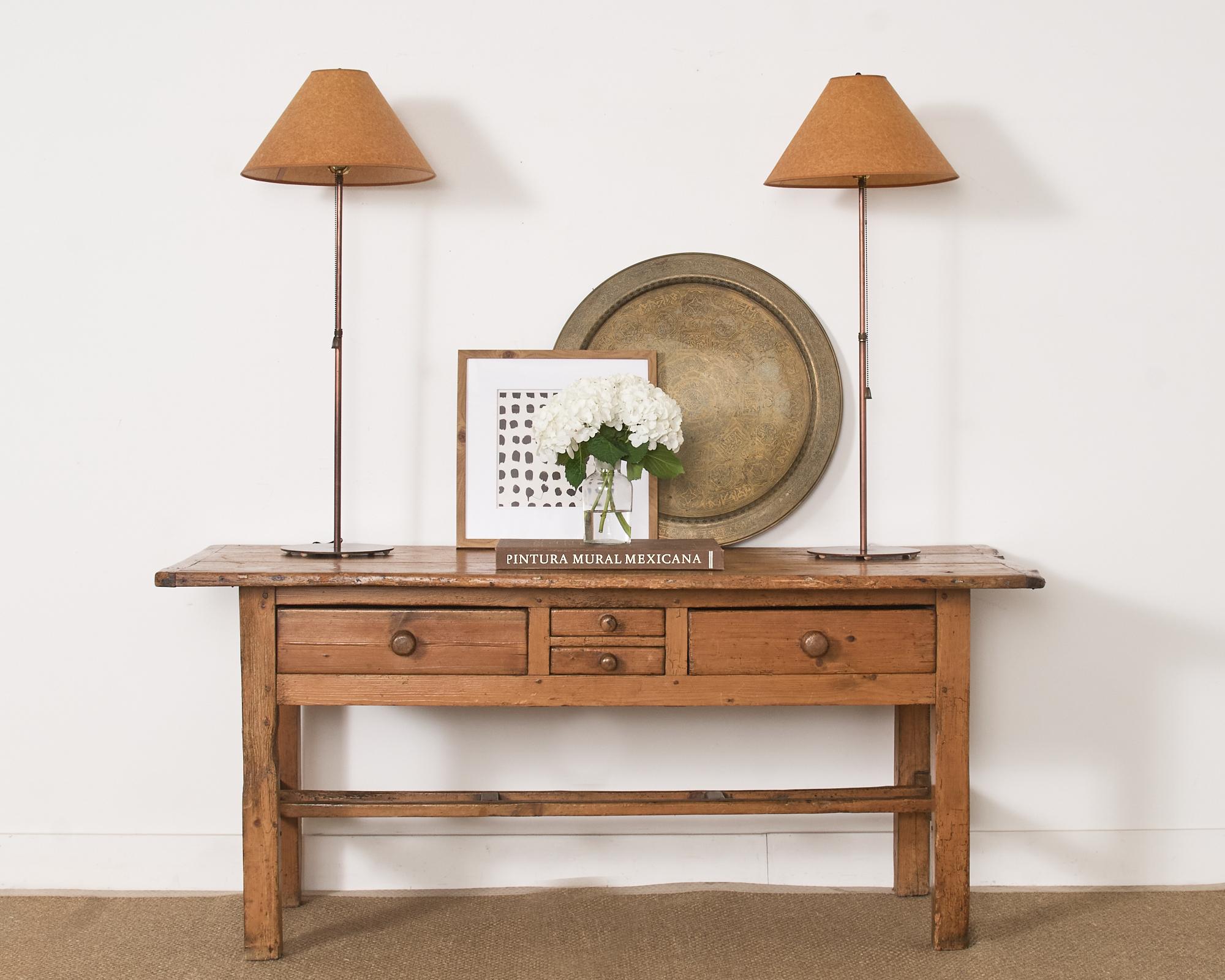 19th century handsomely weathered country English farmhouse work table or console table crafted from fruitwood and pine. The table features a 1 inch thick plank top with breadboard ends. The top is supported by a trestle base fronted by two large