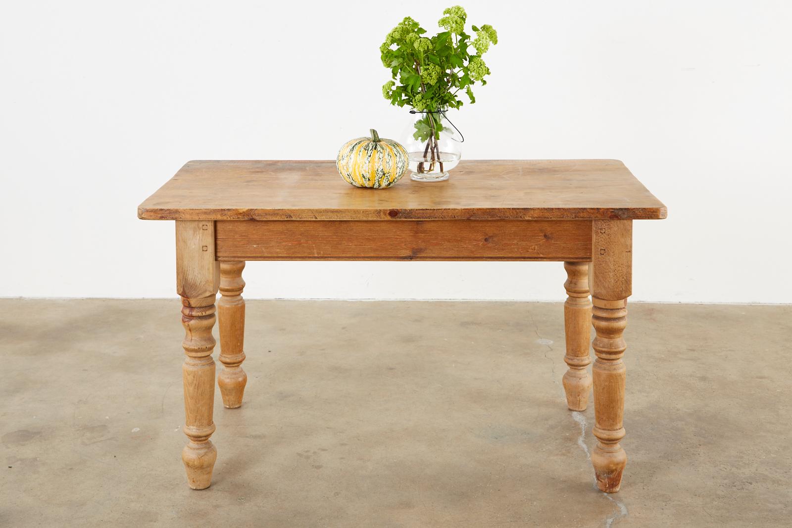 Rustic country English farmhouse dining table or harvest table featuring a 1.25 thick pine plank top. Constructed with wood peg joinery on the legs and modern updates underneath to make it very strong and stable. Supported by thick, chunky turned