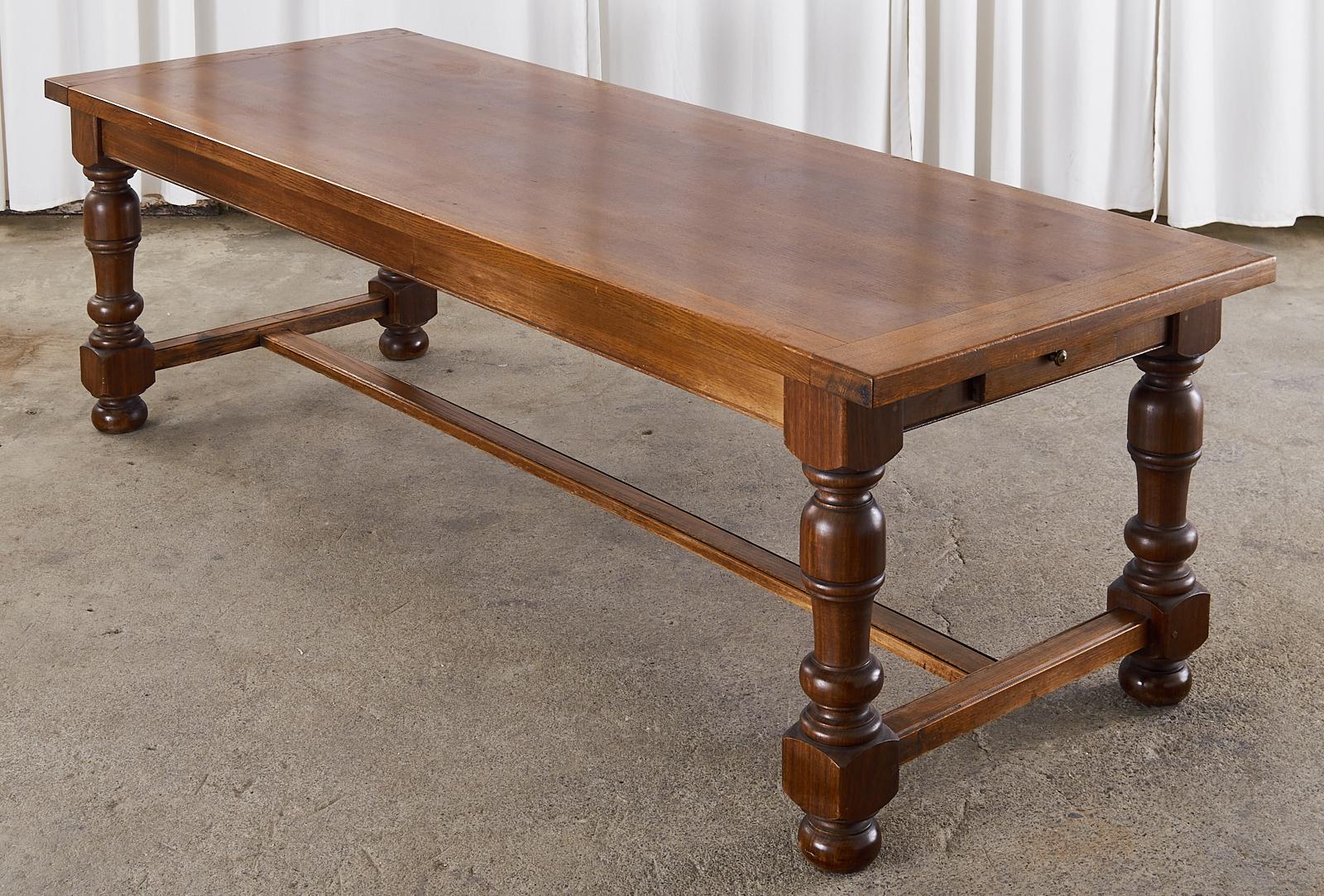 Large country English provincial farmhouse dining table hand-crafted from oak. The top features oak planks nearly 2 inches thick with breadboard ends and showcases the rich oak woodgrain patterns. The trestle style base has a small storage drawer on