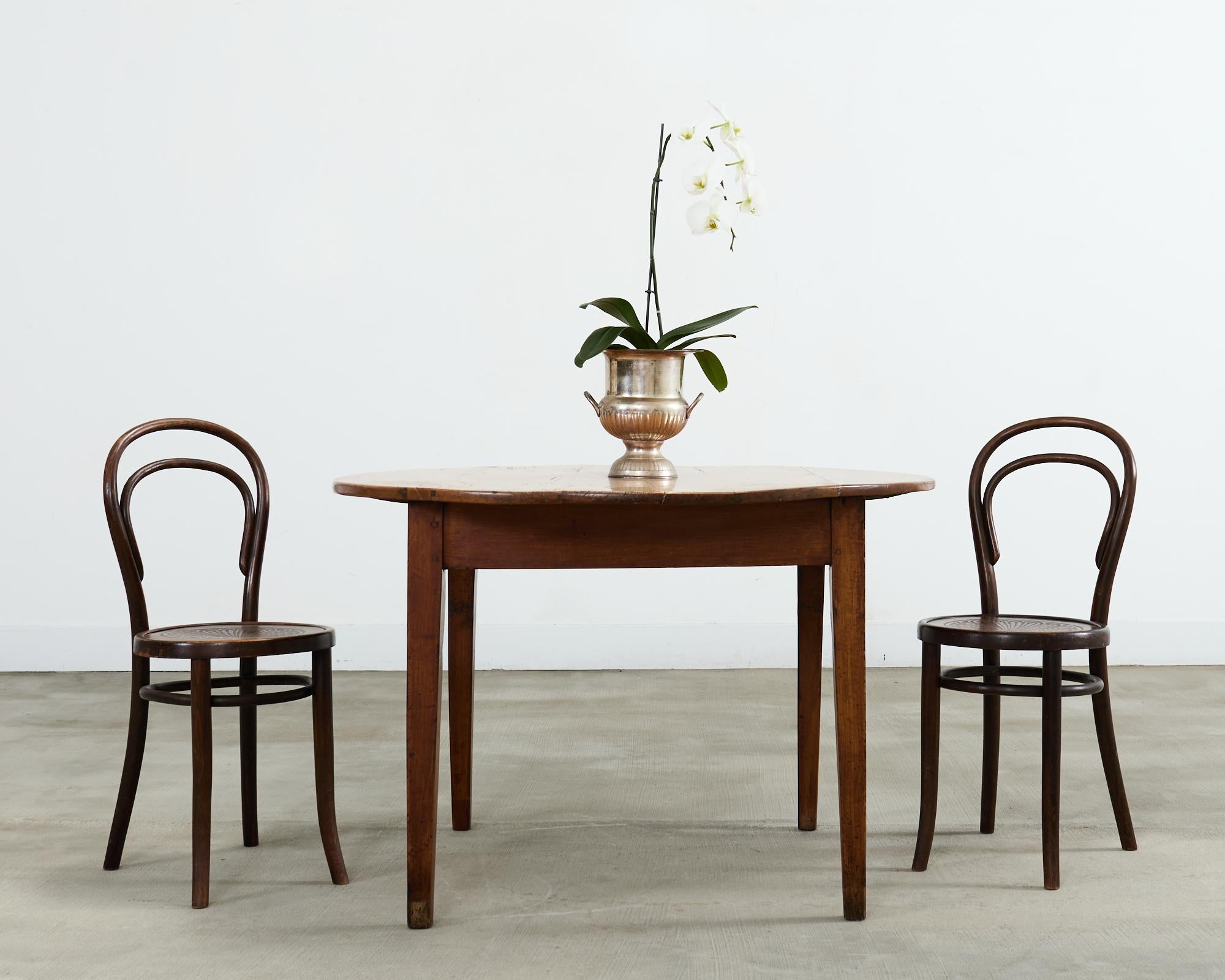 Charming 19th century country English provincial farmhouse dining table crafted from fruitwood. The round table features a large pull-out work table measuring 22 inches wide by 26 inches deep. The fruitwood planks have a distressed, weathered patina