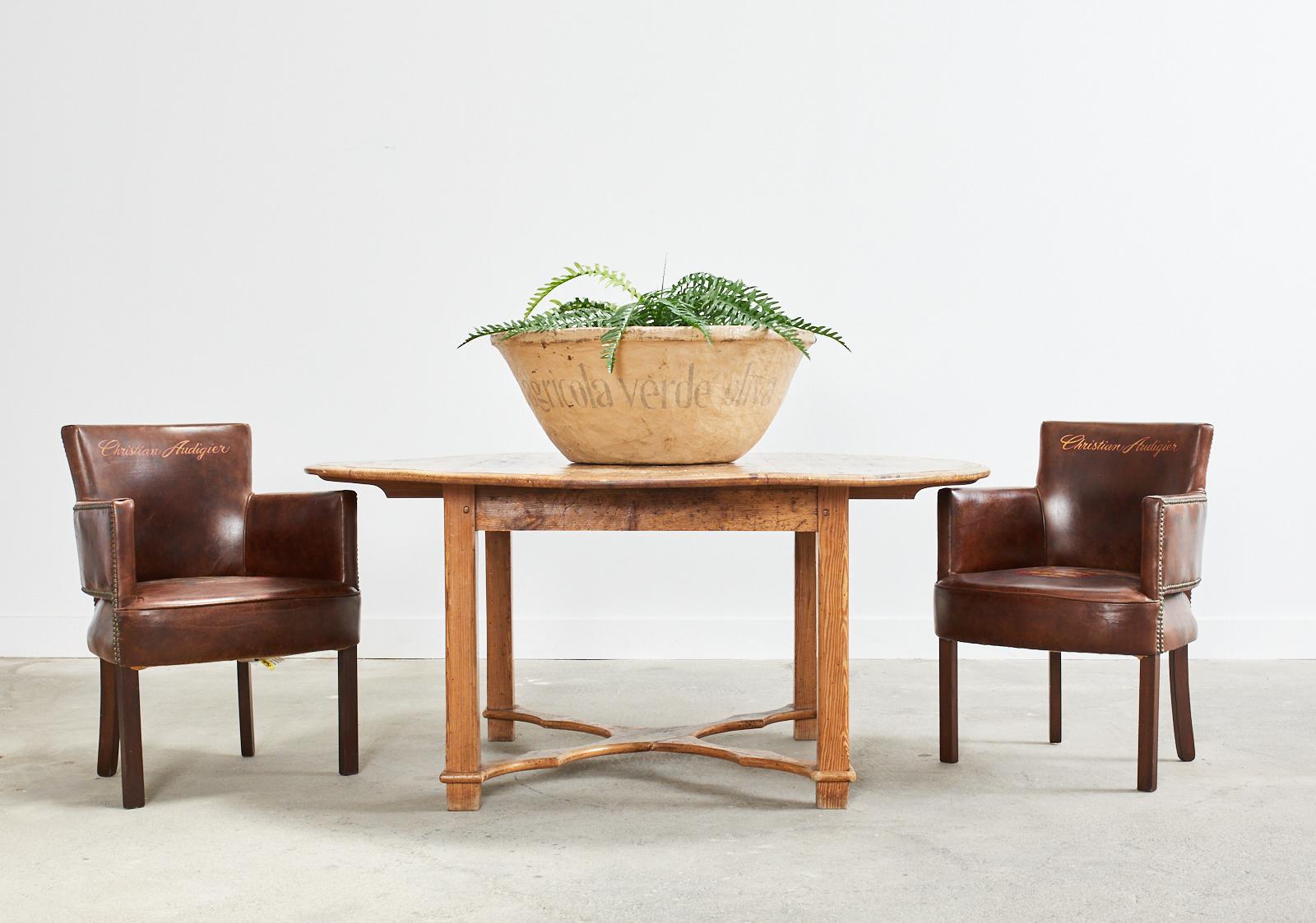 Gorgeous country English pine dining table or center table featuring a 1 inch thick near round top. Crafted from hand-hewn pine planks with a beautifully aged patina on the finish. The top is supported by square chamfered legs conjoined by a shaped
