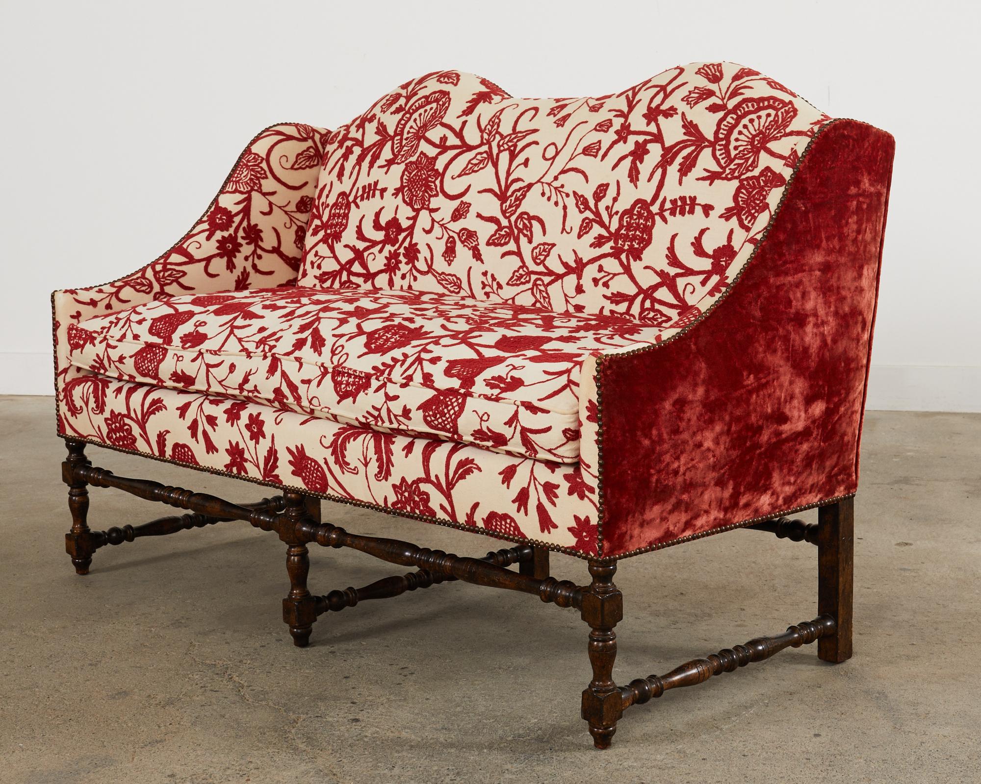 Charming William and Mary or country English style walnut settee custom made by Louis Mittman. The settee features a beautifully crafted walnut frame upholstered in a Brunschwig and Fils style crewel work fabric. The fabric has a spectacular floral