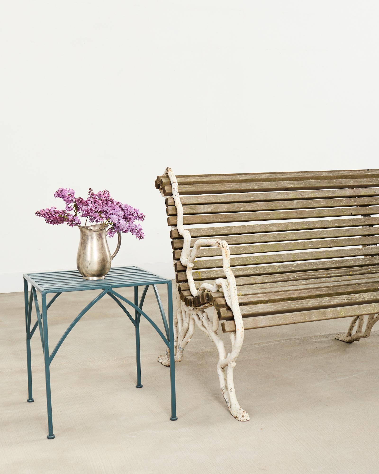 Grand banc de jardin d'époque victorienne anglaise avec des pieds en faux bois en fonte. Les pieds sont reliés par des lattes de bois et l'assise est ergonomique et gracieusement incurvée. Le fer présente une patine d'usure sur la finition peinte,