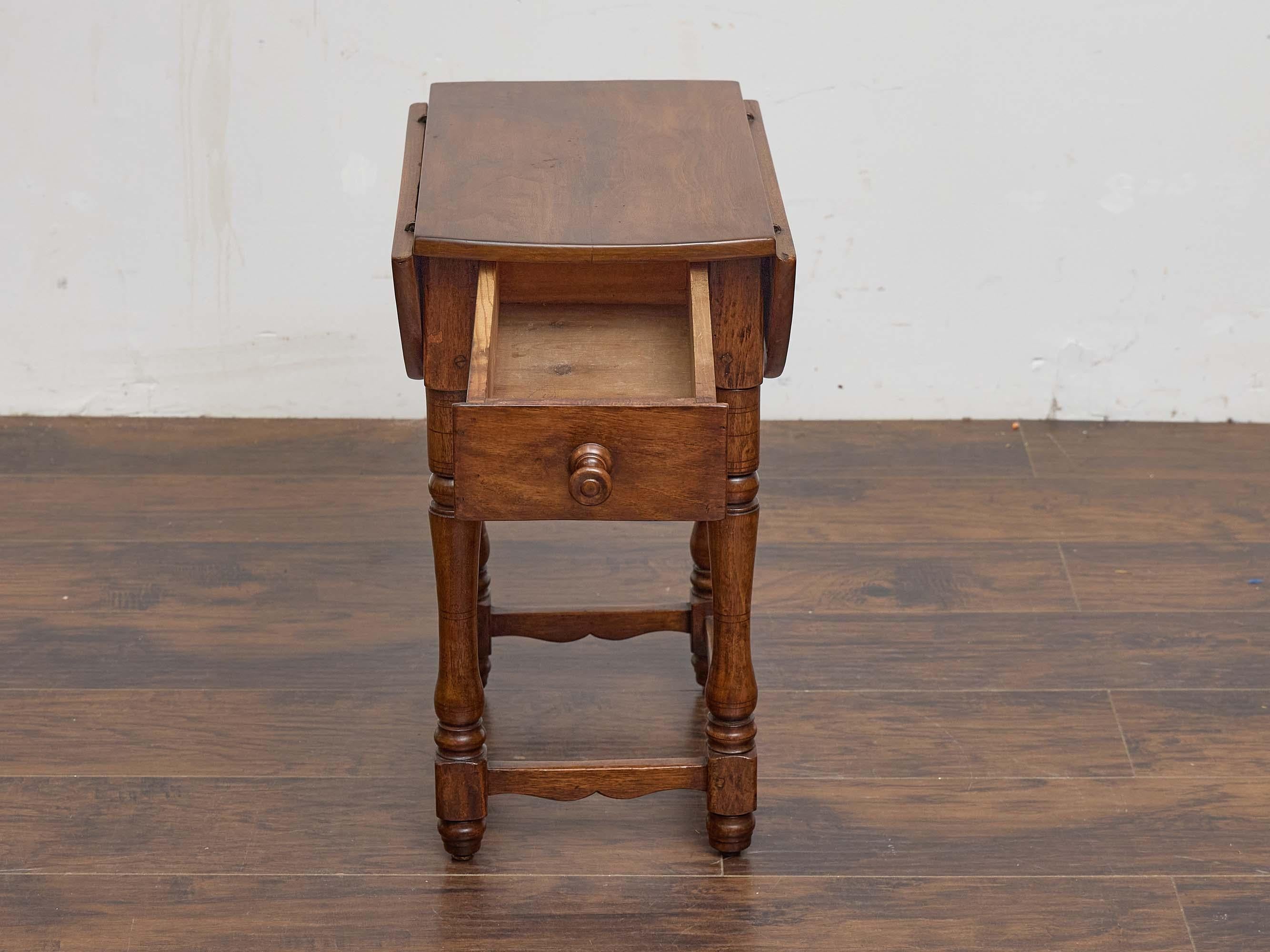 Une table à feuilles tombantes du 19e siècle, pleine de caractère rustique et de charme quotidien. Fabriquée en chêne, la table présente un plateau rectangulaire avec deux feuilles tombantes qui peuvent être relevées lorsque l'on a besoin d'une