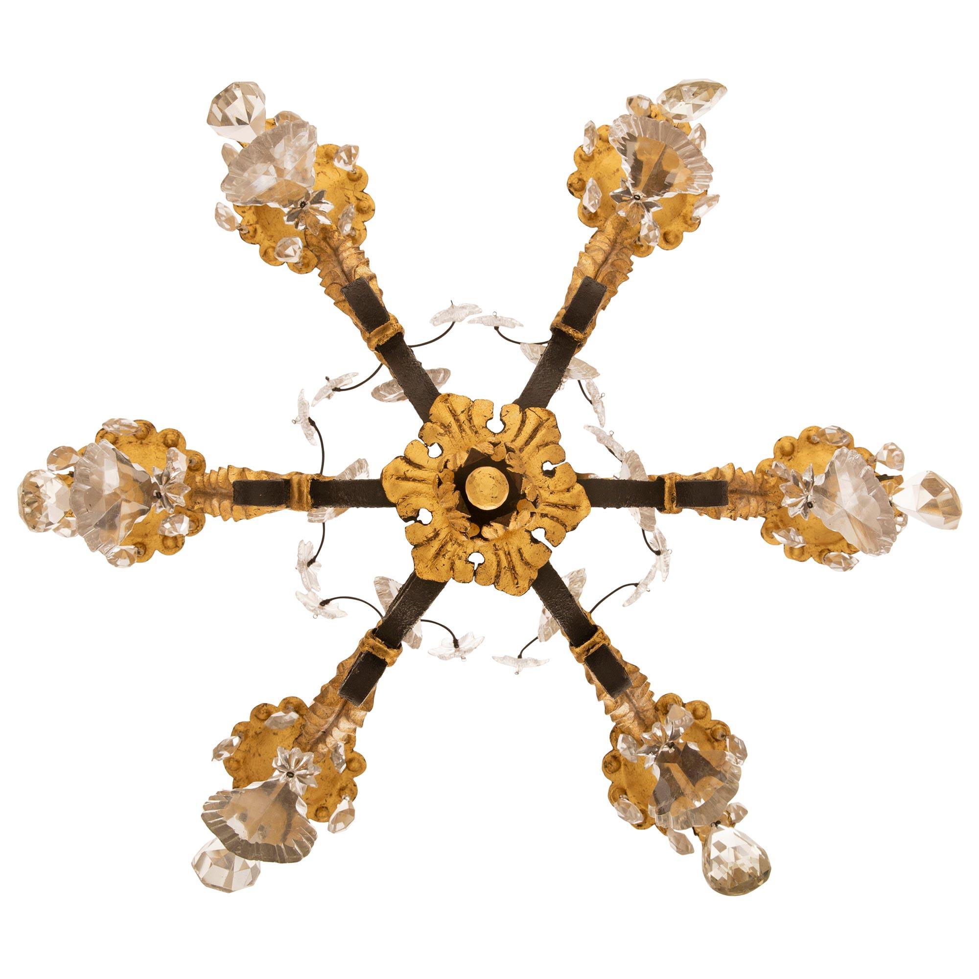 A beautiful Country French 19th century Louis XV st. wrought iron, gilt metal and crystal chandelier. The six arm chandelier is centered by a lovely gilt metal floral bottom finial with lovely most decorative scrolled wrought iron movements adorned
