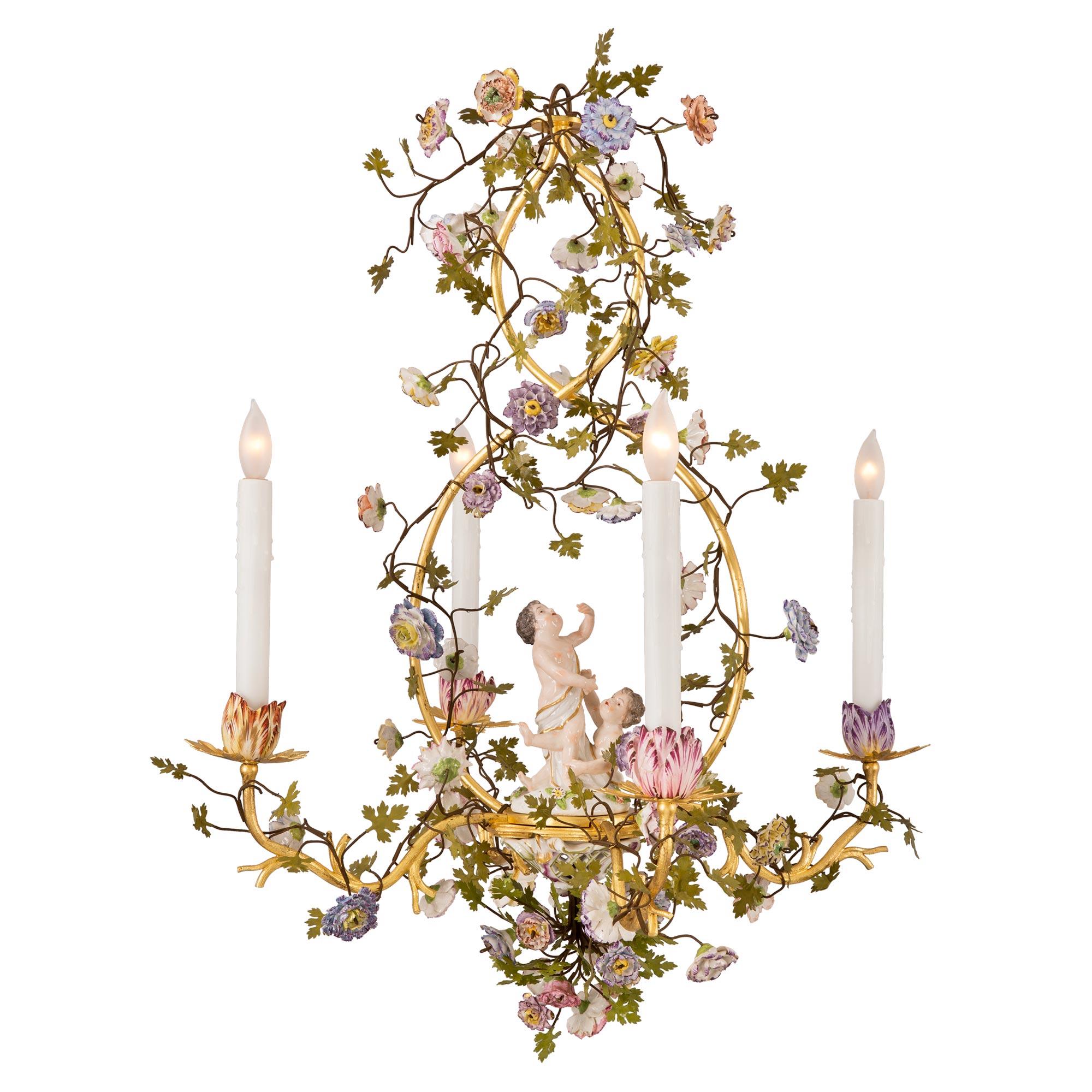A lovely Country French 19th century Louis XVI st. gilt metal, tole and Saxe porcelain four arm chandelier. The chandelier is centered by wonderfully executed and most charming Saxe porcelain flowers with fine tole leaves. The scrolled gilt metal