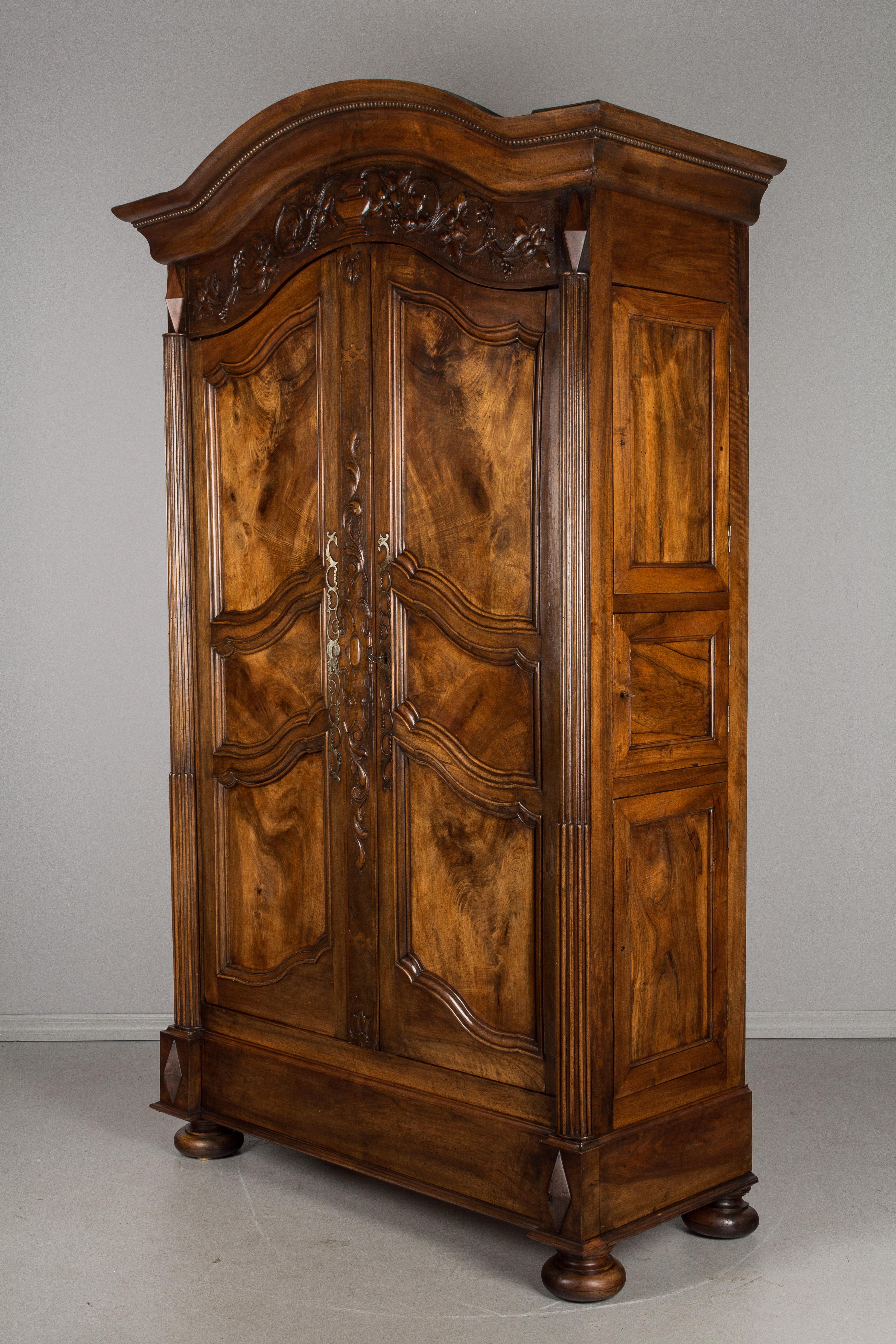 A large early 19th century French armoire from Burgundy, made of solid walnut. Three book-matched panels of burled walnut with boldly patterned knots are nicely framed on each door. Interior has two shelves and one shelf with three dovetailed