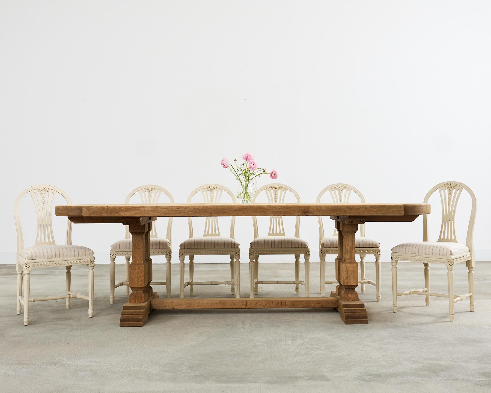 Substantial country french provincial farmhouse dining table crafted from solid oak. The large table features a 3 inch thick top crafted from oak timbers having round notched demi-lune ends. The top is sectioned in a parquet style and supported by a