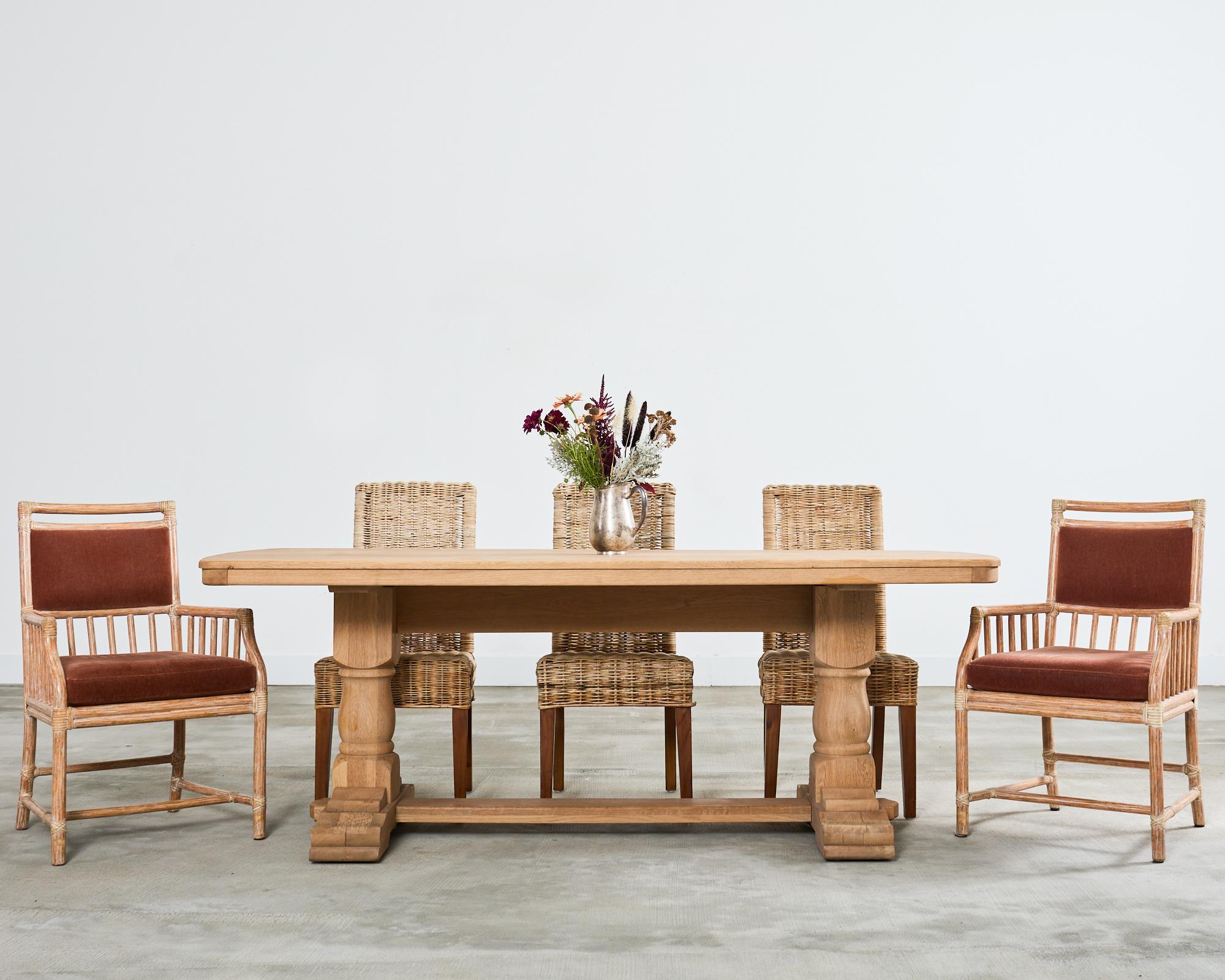 Magnifique table de salle à manger à tréteaux de style campagne française, avec finition en chêne blanchi. La table est dotée d'un épais plateau rectangulaire aux extrémités arrondies qui mettent en valeur les incroyables veinures du chêne. Le