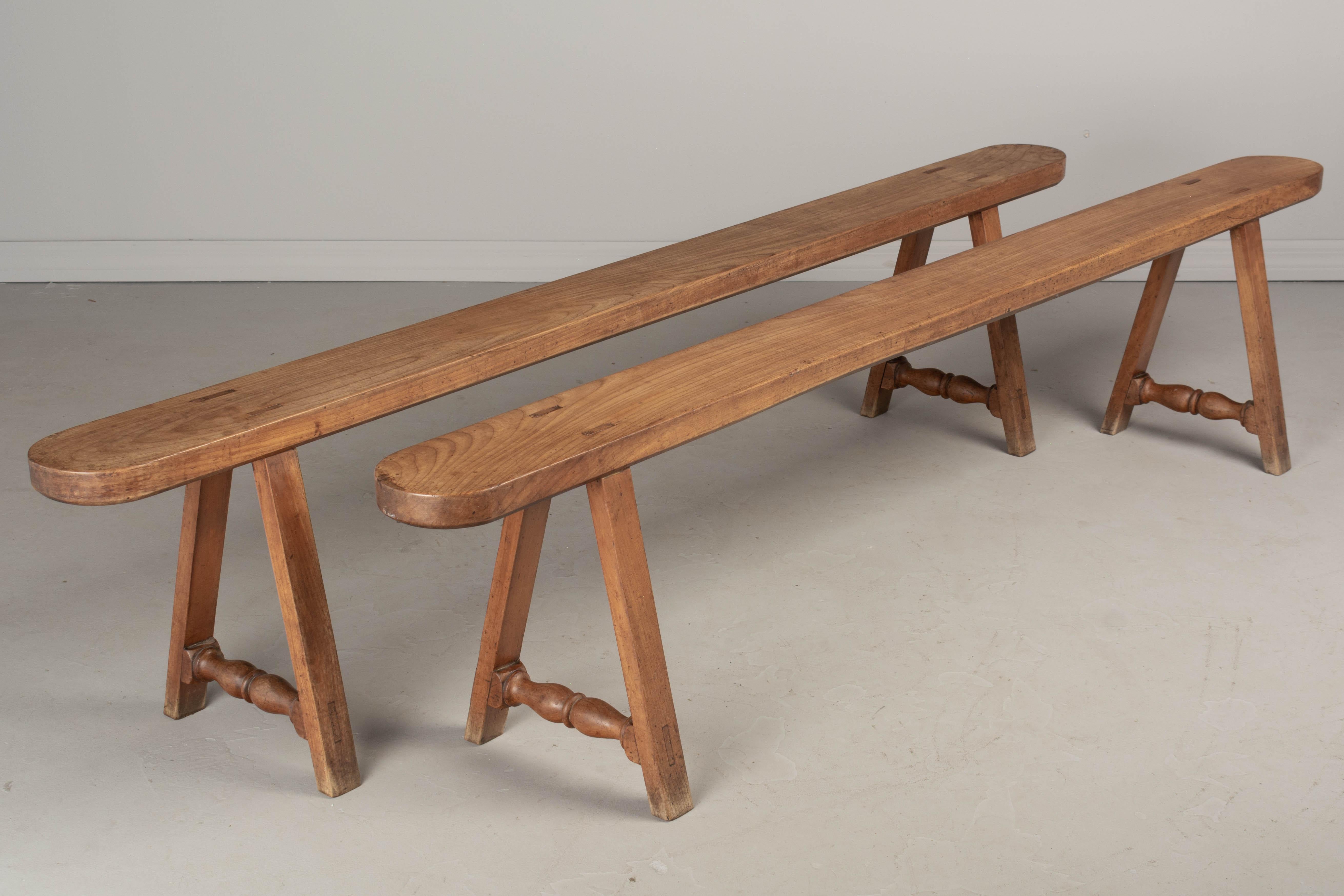 A pair of Country French benches from Normandy made of solid cherry wood. Sturdy craftsmanship with mortise and tenon construction. Waxed finish. Circa 1900s. 79