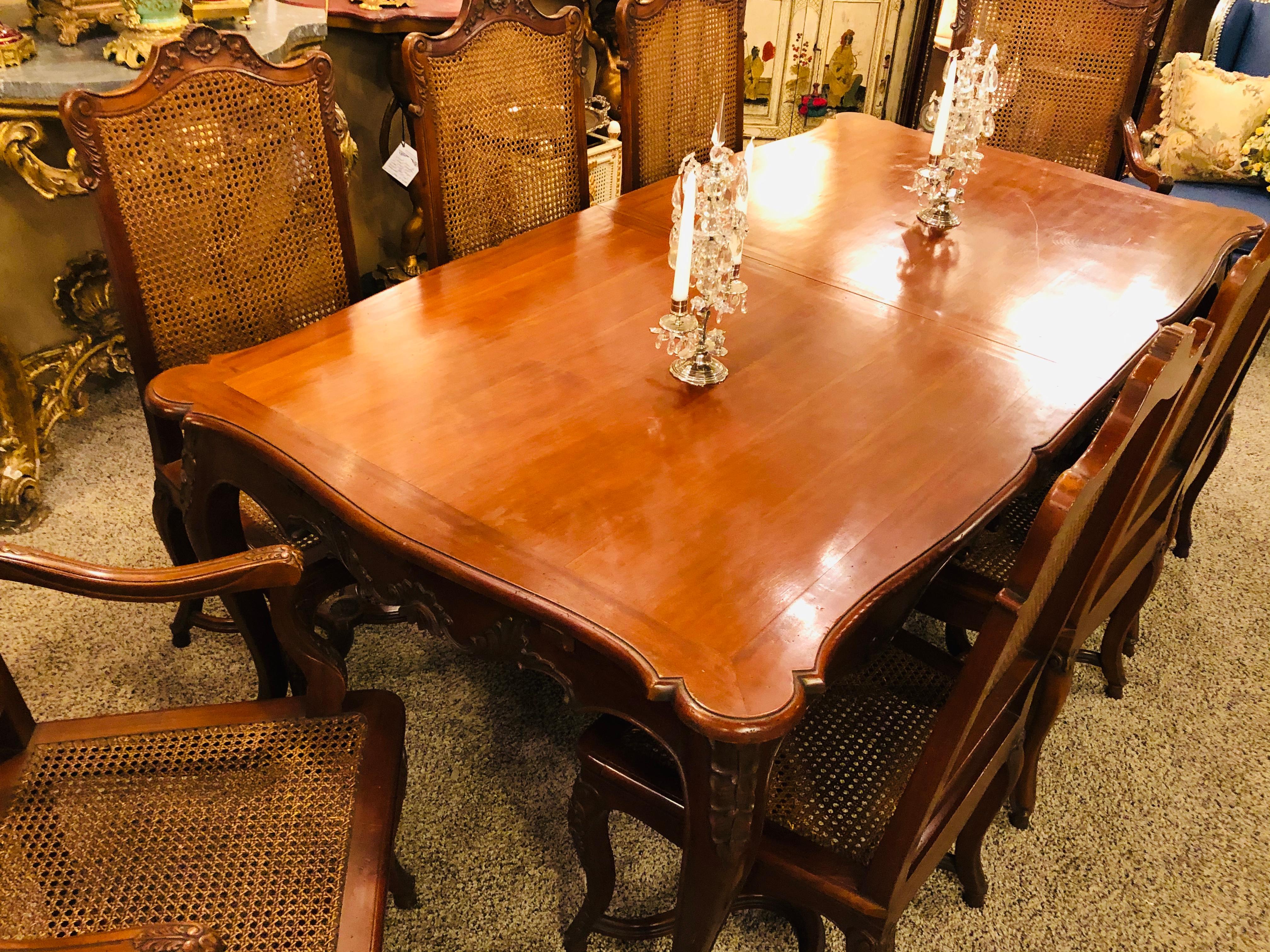 Country French dining table and eight chairs. Dining room set. A finely carved Rococo style country French dining table having two 17.75 inch leaves and a set of eight dining chairs. A fine addition to any holiday setting. No one would be