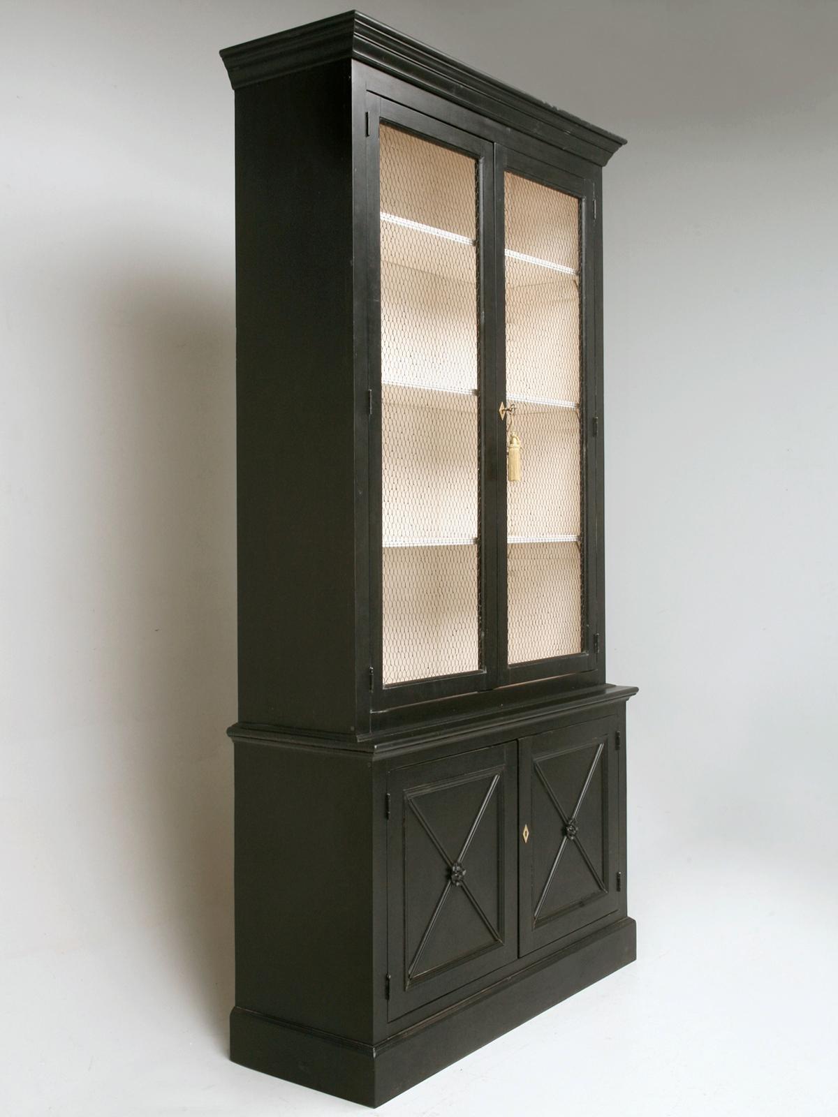 Custom Country French inspired handmade 4-door bookcase, in the Directoire style, finished with a black brushed painted exterior, French vanilla interior and European style chicken wire in the upper doors. Crafted by hand here in our own Chicago