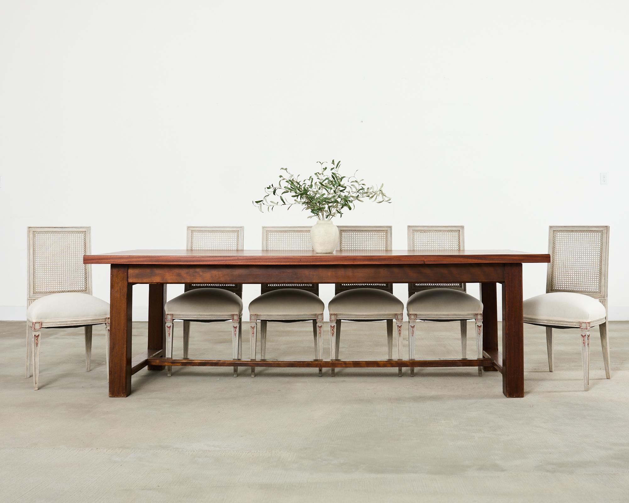 Gorgeous 20th century country French farmhouse dining table featuring a rare mahogany construction. The table has a 2 inch thick solid mahogany plank top having a straight edge border. The top is supported by a massive trestle base with 4 inch thick