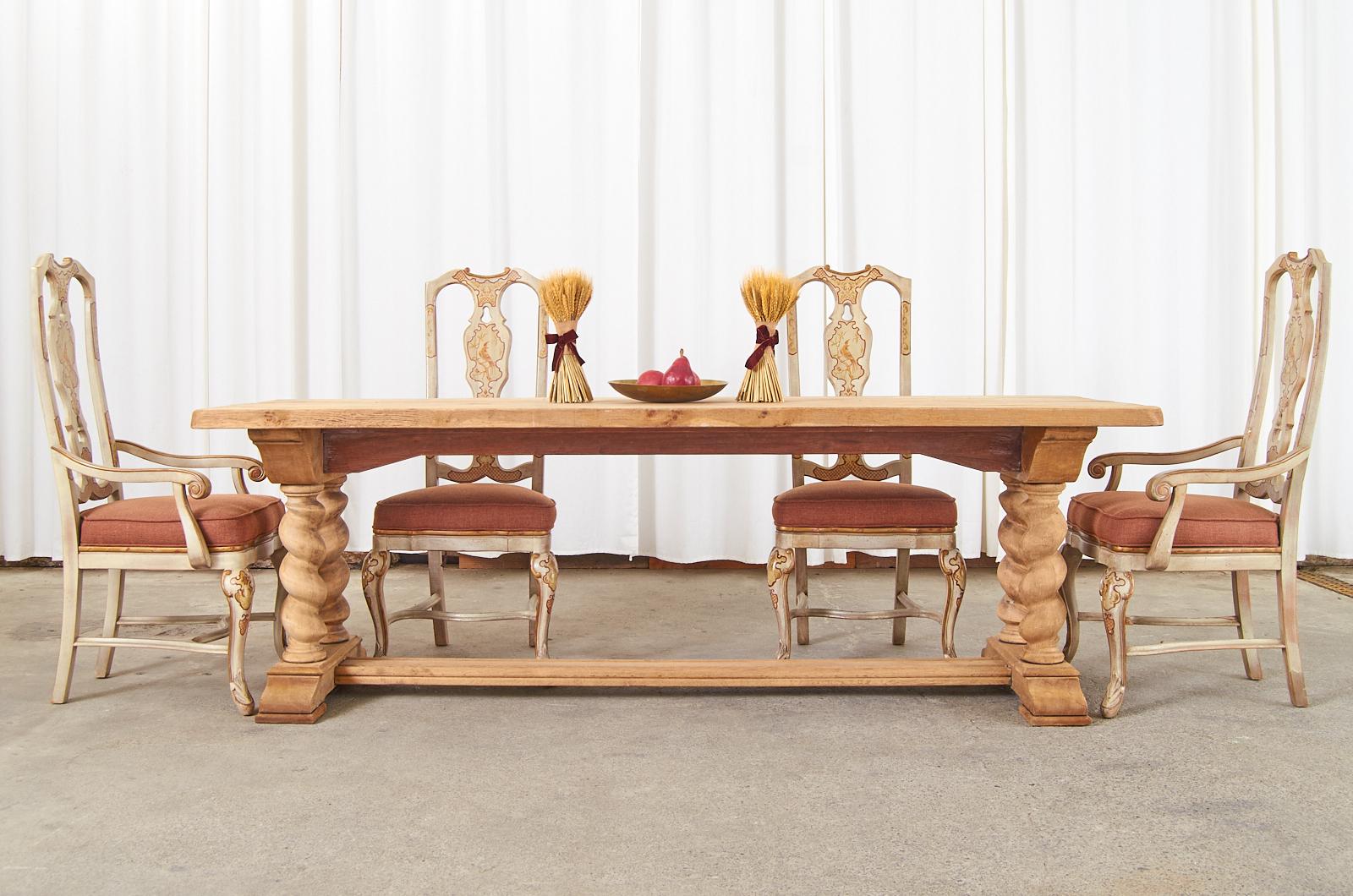 Rustic country French farmhouse trestle dining table crafted from bleached oak. The table features a large trestle base with thick, chunky baroque style barley twist legs ending with shoe feet. The base is topped with a nearly 2 inch thick plank top