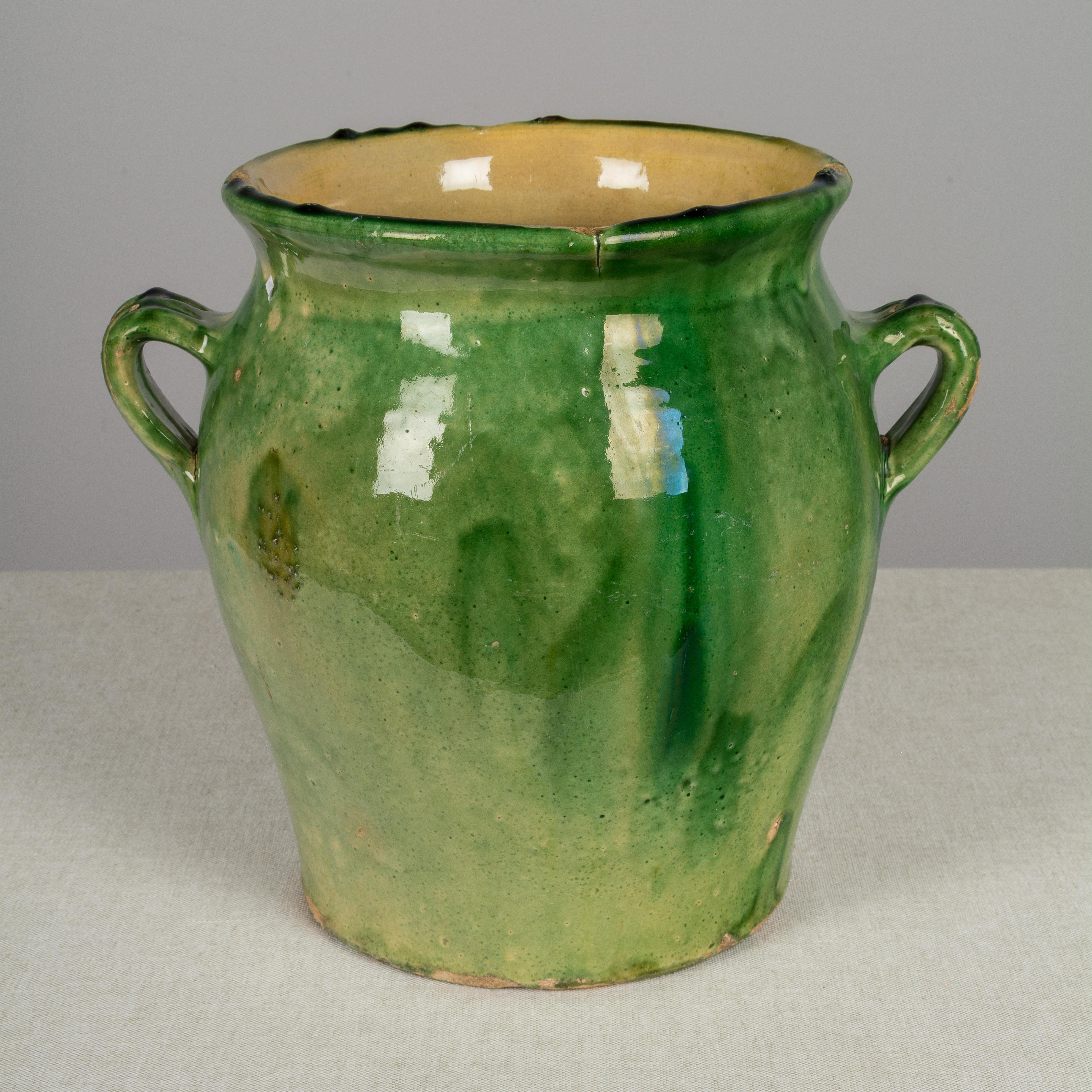 An earthenware confit pot from the Southwest of France with traditional green glaze. These ordinary earthenware vessels were once used daily in the French country home and have beautiful rustic glazes of green, ochre and terracotta. Nice decorative