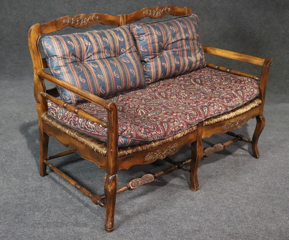 This is one of two available. This beautifully distressed country French settee features high quality upholstered cushions and naturally distressed rush seating from use. This will be one of your favorite places to sit and can be used in many