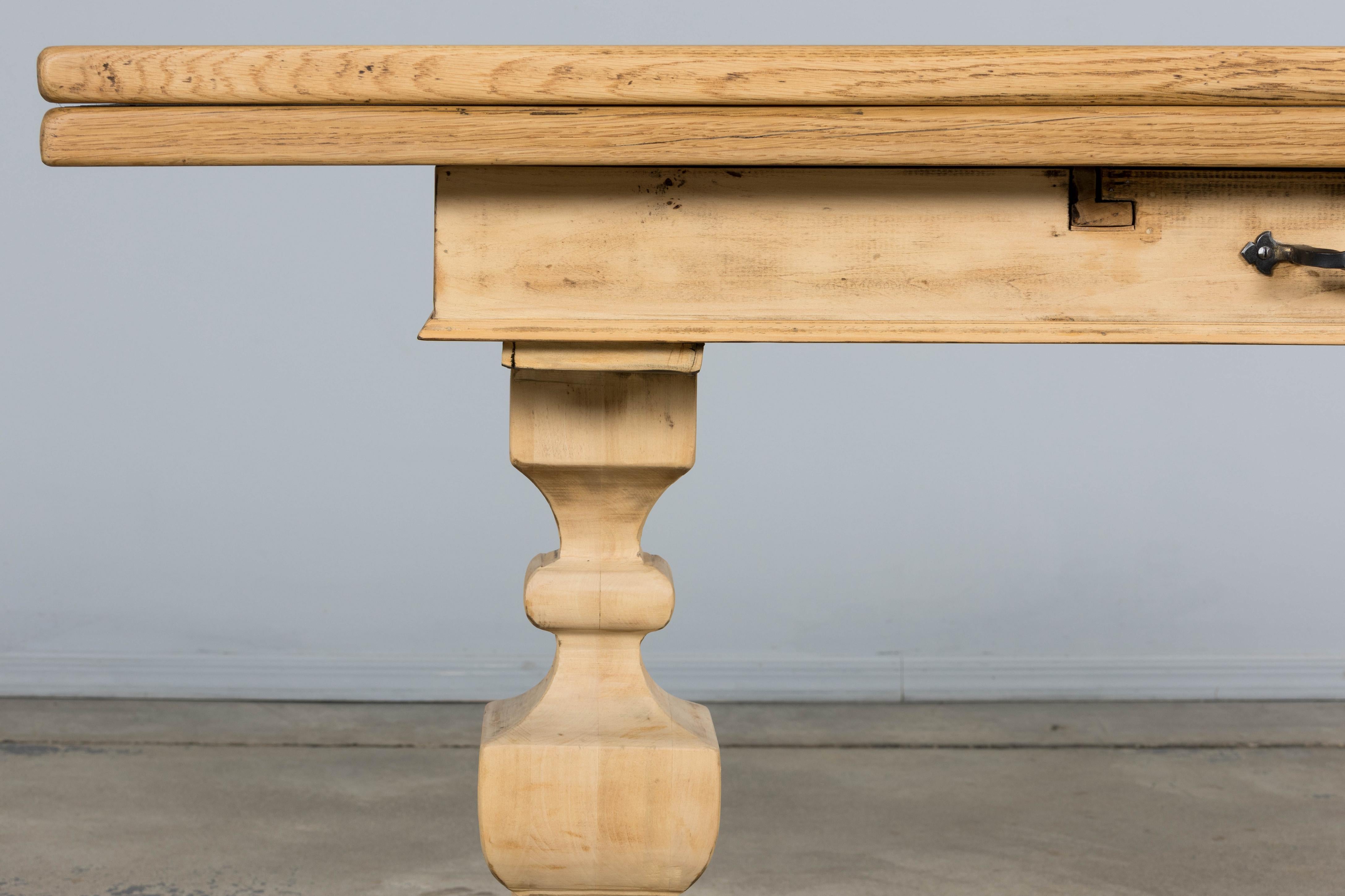 A lovely French Country Louis XIII style trestle table in a beautifully bleached wood finish, dating to the mid 20th century and sourced in Provence, France. The table features a rectangular top in a soft blond tone that highlights the natural