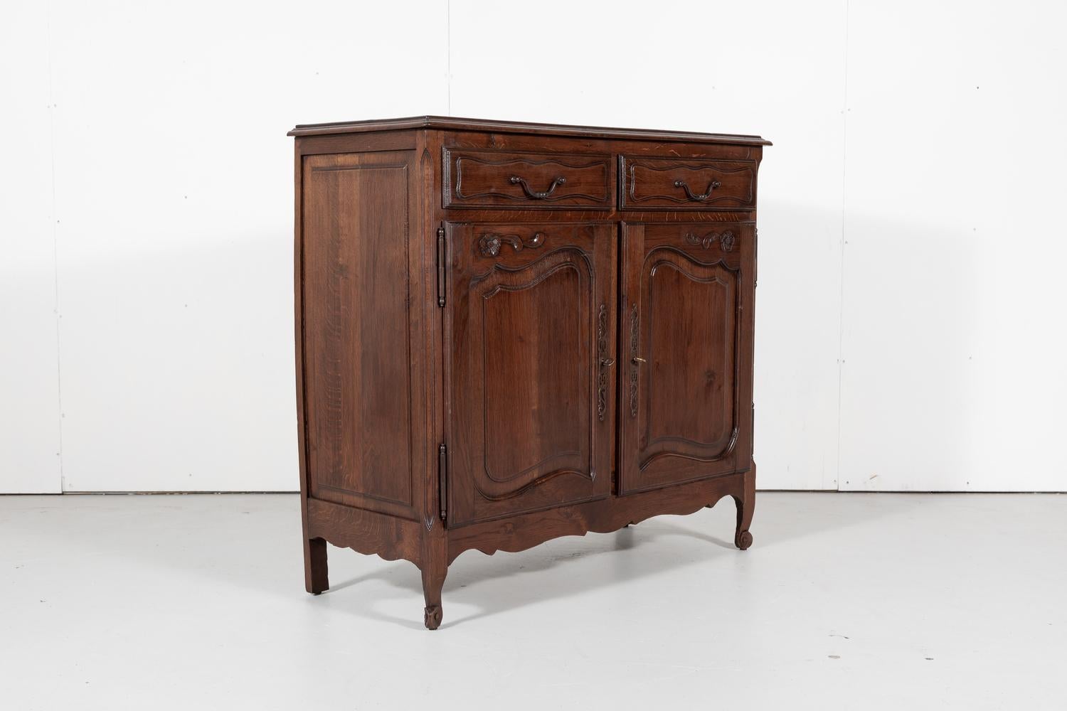 Charming country French oak Louis XV style buffet d'appui or gentleman's buffet, circa 1930s. Two drawers over two doors above a scalloped apron with foliate carvings. Rests on short cabriole legs ending in scrolled toes. Gentleman buffets like this