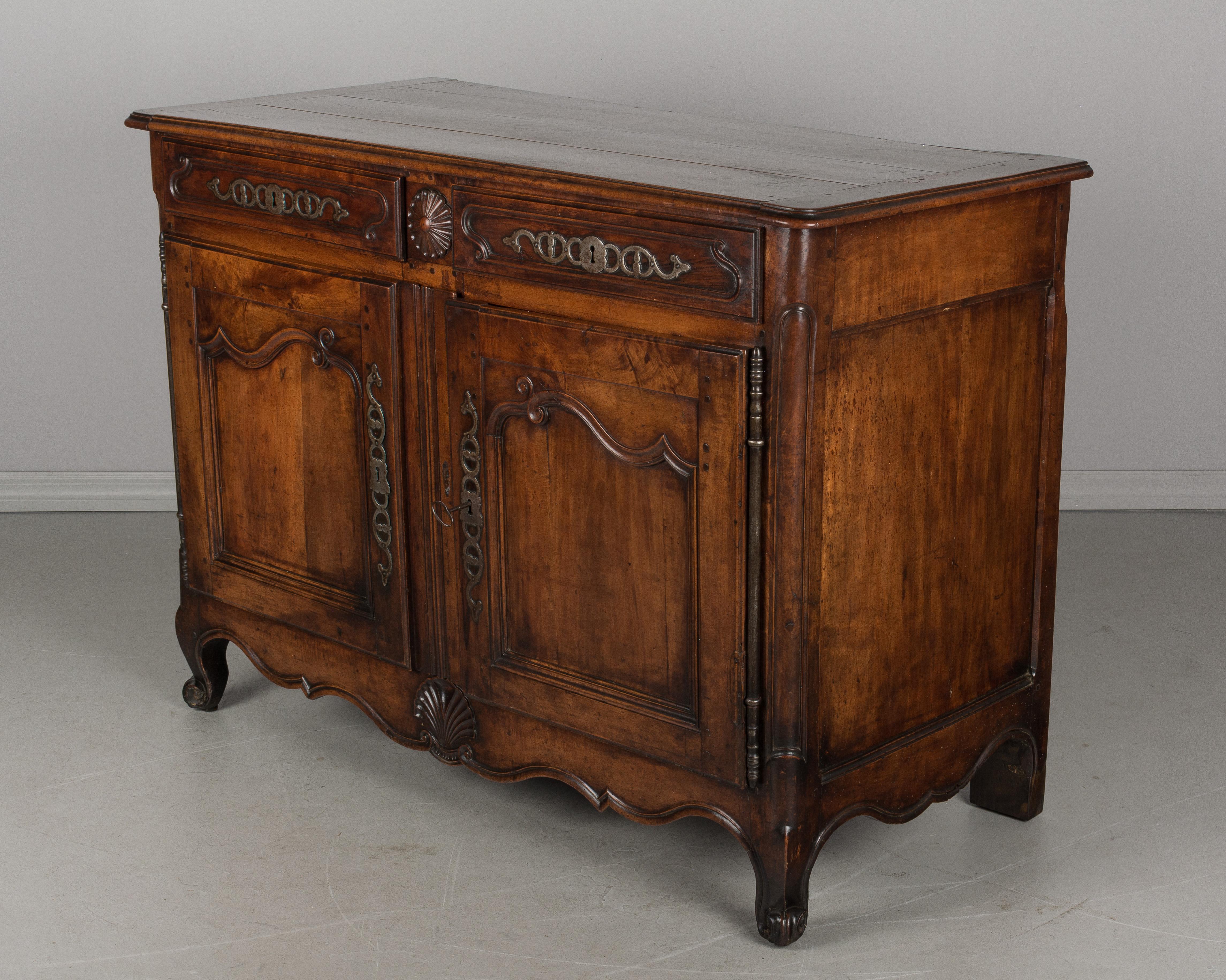 An early 19th century Louis XV style French buffet from the Loire Valley made of solid apple wood. Beautiful character to the wood and simple hand-carvings including a scalloped apron with large shell motif. Interior provides ample storage, opening