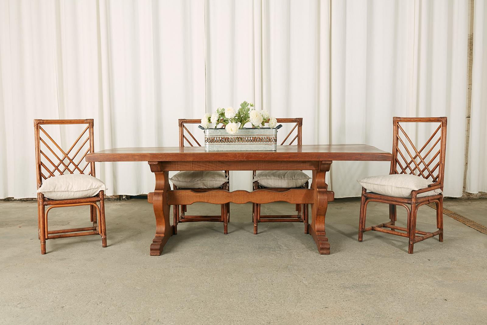 Rustic country French farmhouse dining table constructed from oak. The table features a 2.5 inch thick solid oak top made from planks. Supported by a trestle style base having shield shaped legs conjoined by a shaped stretcher. The pair of legs have