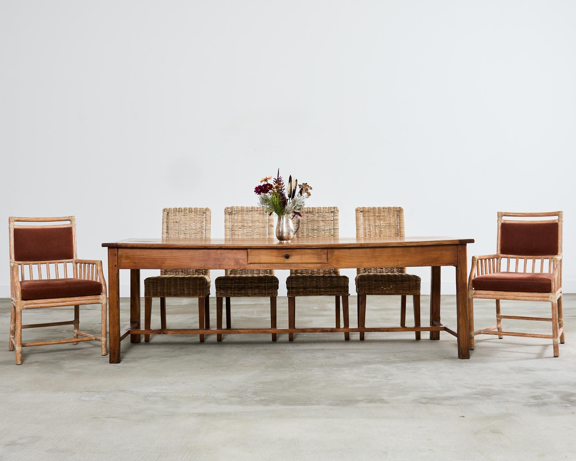 Handsome 20th century country French provincial farmhouse dining or harvest table crafted from fruitwood. The table features a thick three plank top with breadboard ends constructed with mostly wood peg joinery. The frieze has two storage drawers on