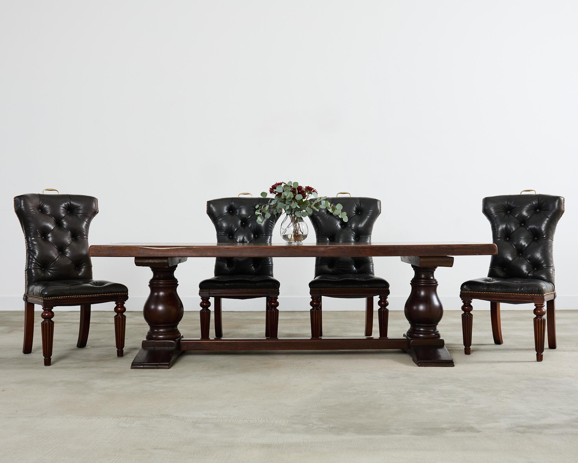 Grand country French provincial style farmhouse trestle dining table crafted from solid oak. The imposing table is made on a massive scale featuring a nearly 3 inch thick top with large butterfly or bowtie joints visible. The top is supported by a
