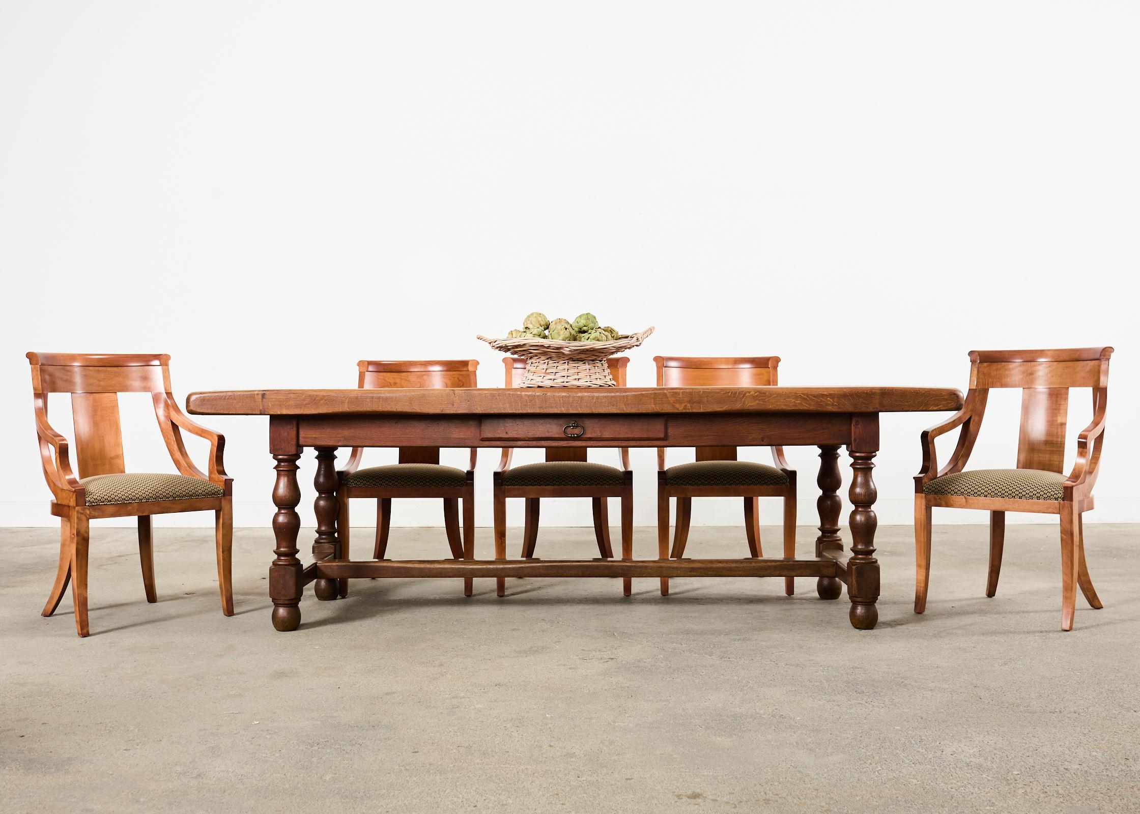 Imposing country French provincial oak farmhouse trestle dining table featuring a parquetry top. The table features a massive 3 inch thick rectangular top with fascinating geometric parquetry inlay which showcases the rich oak woodgrains. The top is