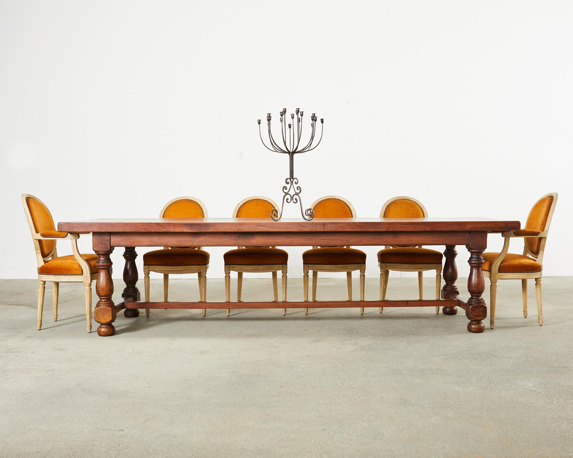 Substantial country French provincial dining table or harvest table hand-crafted from oak timbers. The monumental top planks are 2.5 inches thick and supported by a trestle style base. Constructed with large wood peg joinery the table has ample