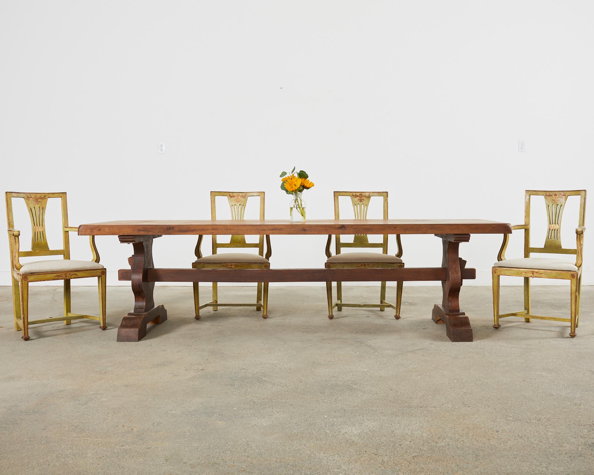Large late 19th century country French provincial farmhouse dining table featuring a trestle style base. Crafted from oak the table top is made with 2.5 inch thick timber planks. The top is supported by hourglass shaped legs conjoined by a large