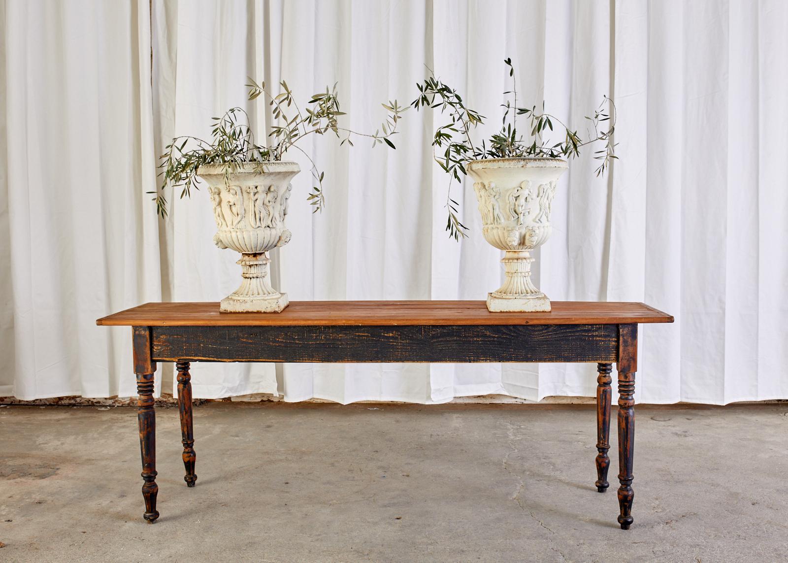 Rustic country French Provincial pine farm table or console table. The table features an intentionally distressed painted finish on the base topped with planks having bread board ends. The table is dining height at 29 inches making it a very