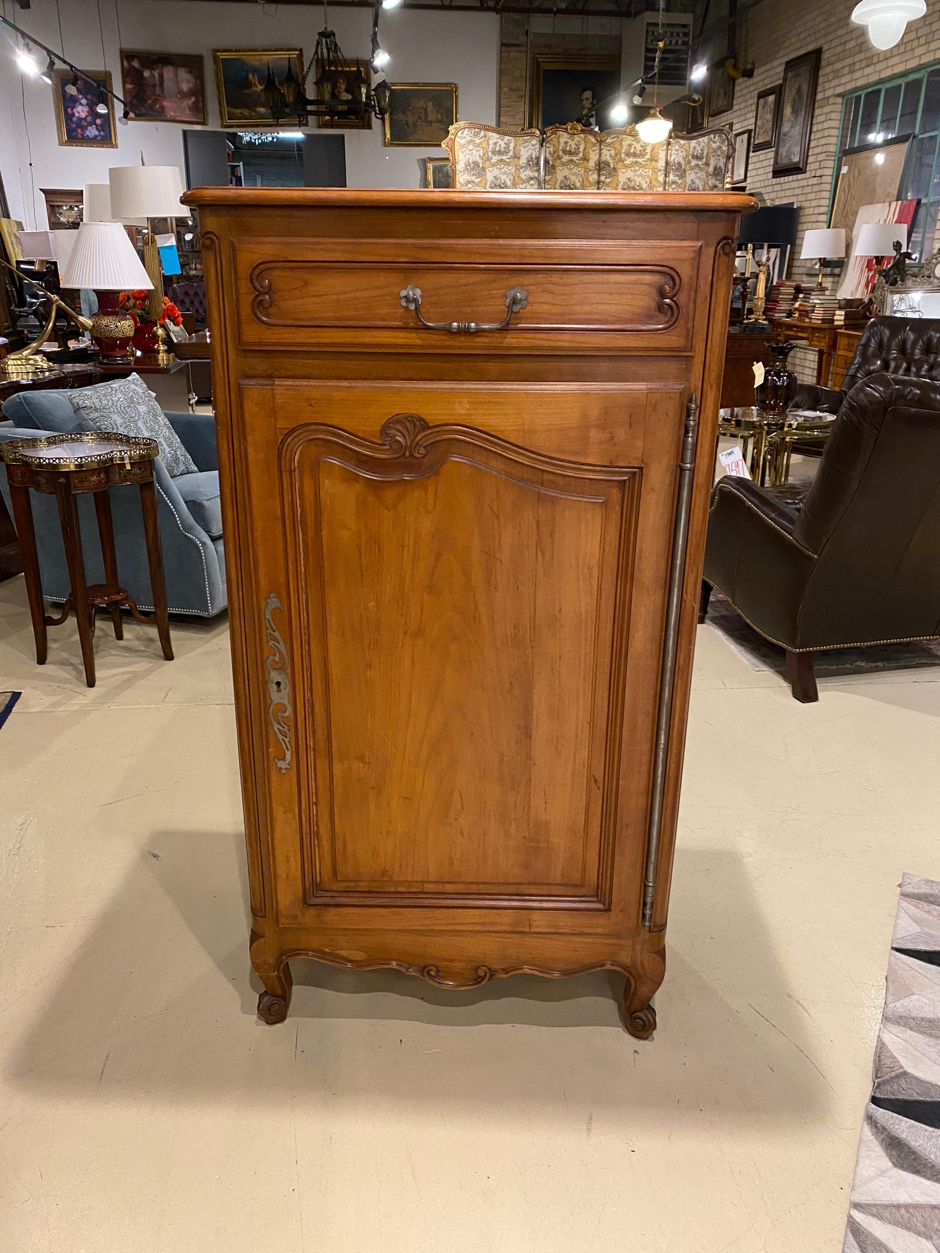 A French Country style cherry jam cupboard. This piece has a lot of storage without a big footprint in the room, but adds a bit of tradition. There is a single drawer above the door and another behind the door.