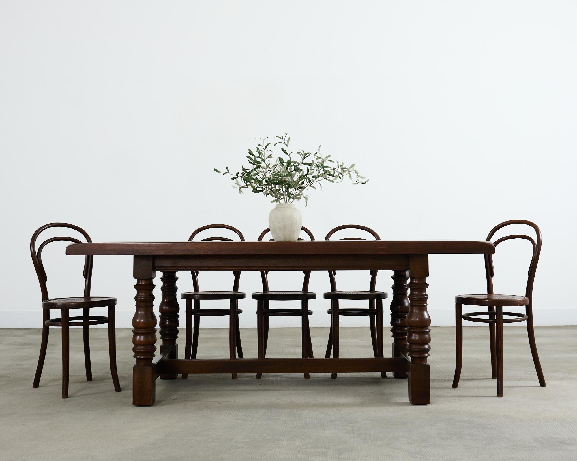 Table de salle à manger de style provincial français des Pays-Bas, fabriquée en chêne. La table est dotée d'un épais plateau rectangulaire soutenu par un piètement à tréteaux. Le tréteau a des pieds tournés épais et massifs, reliés par un châssis à